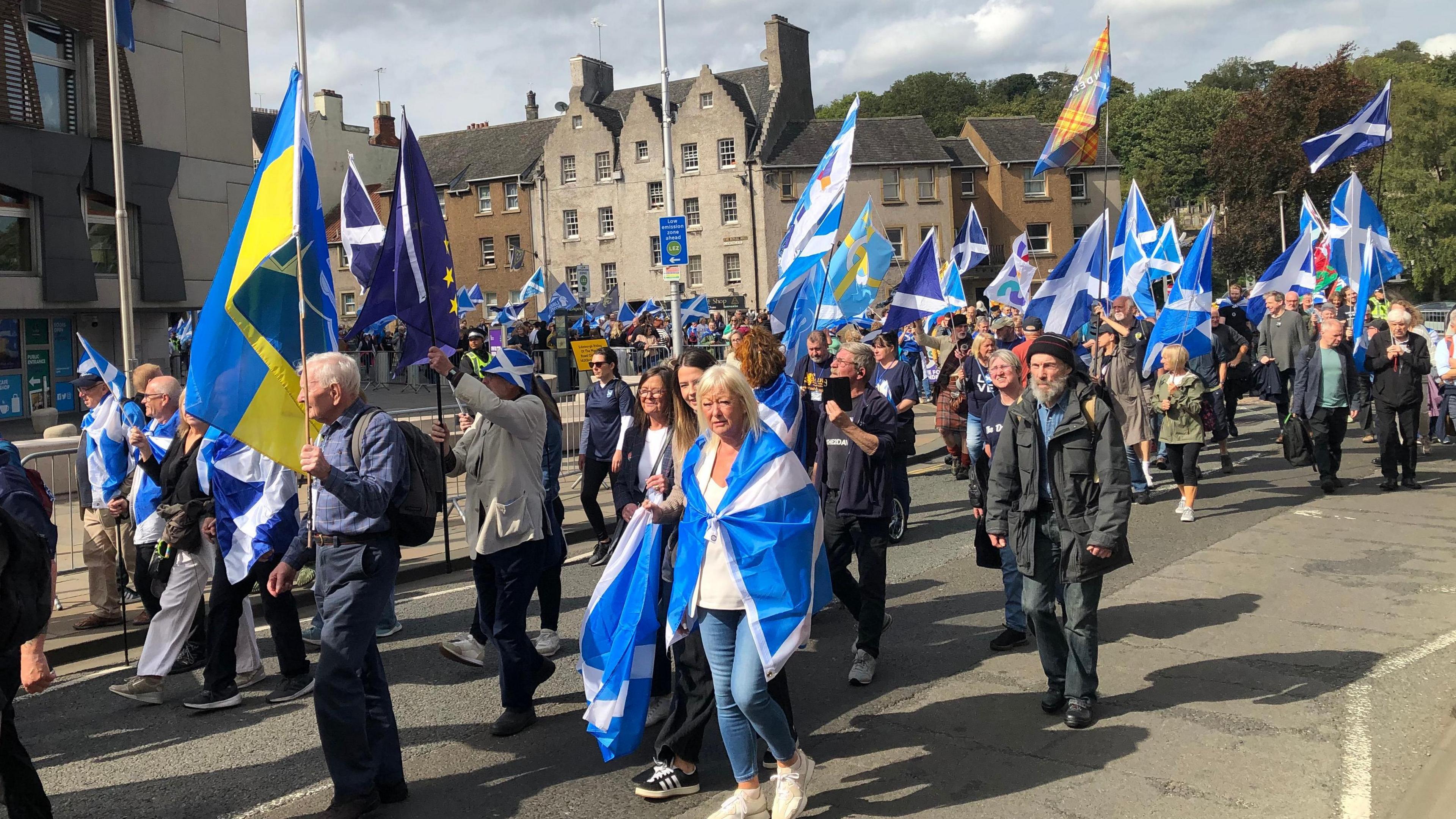 A large group of people waving Scotland flags and pro-independence Yes flags