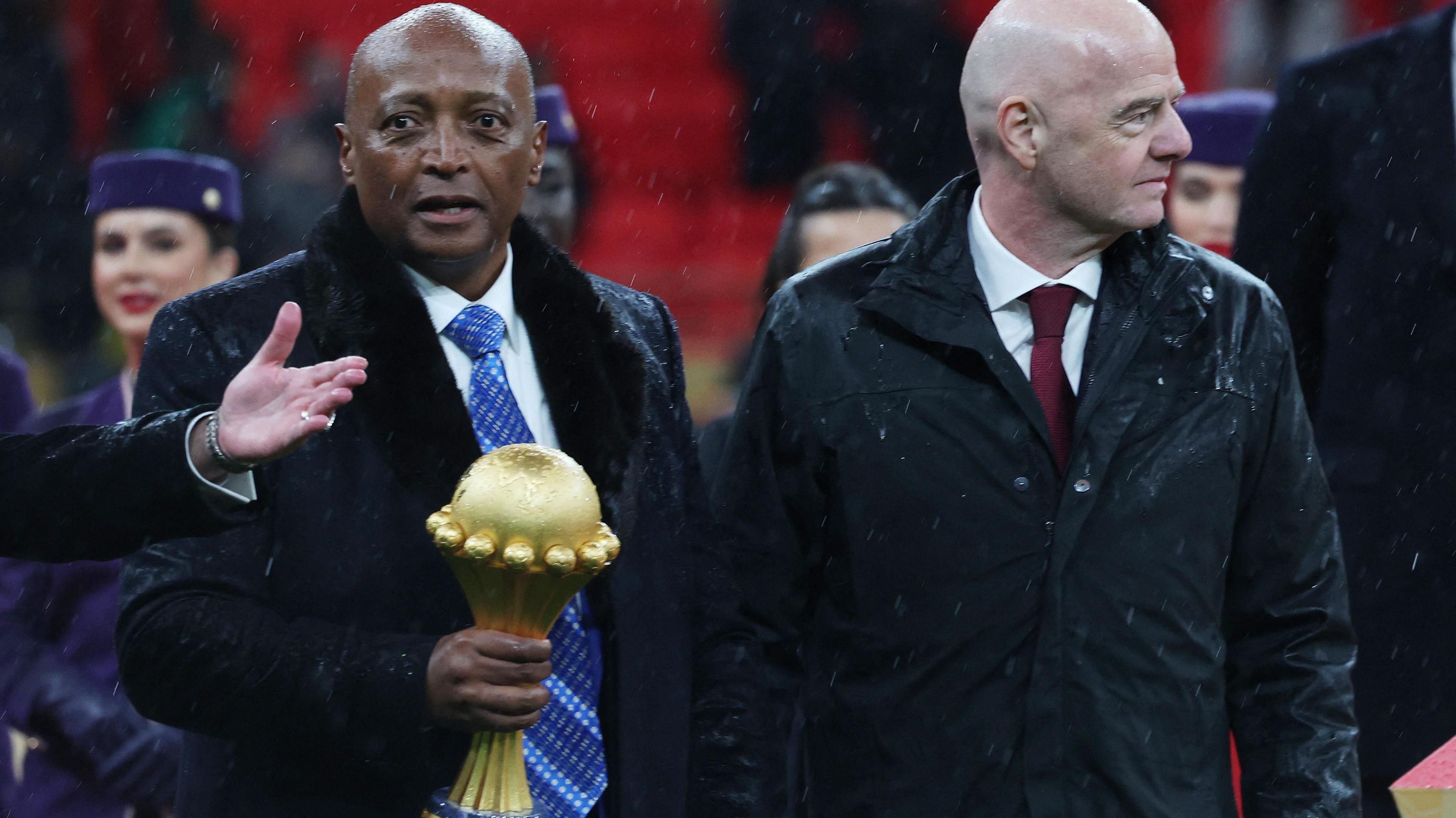 Confederation of African Football president Patrice Motsepe holds the Africa Cup of Nations trophy while he walks alongside Fifa president Gianni Infantino