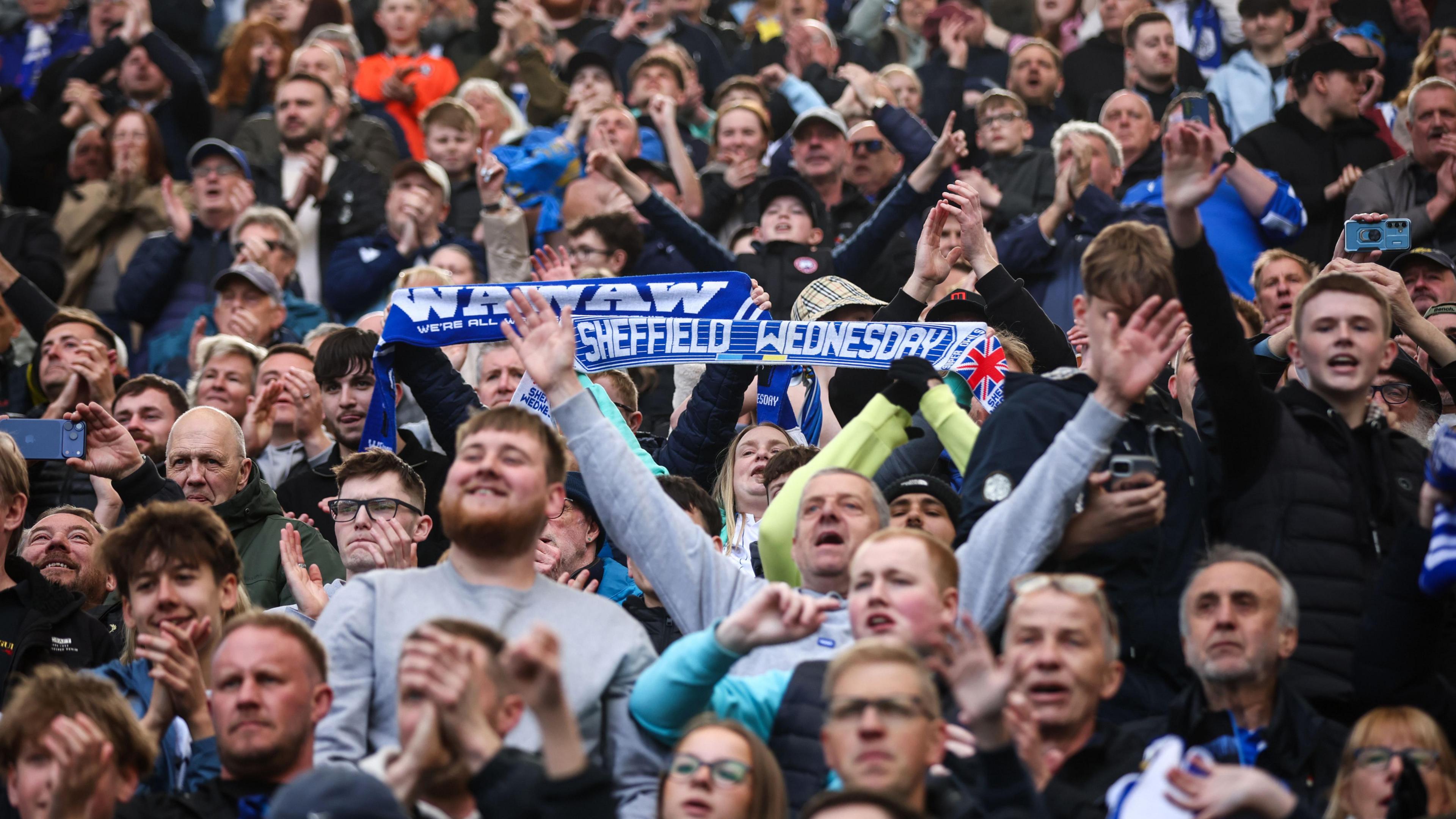 Sheffield Wednesday fans, two of them holding scarves above their head