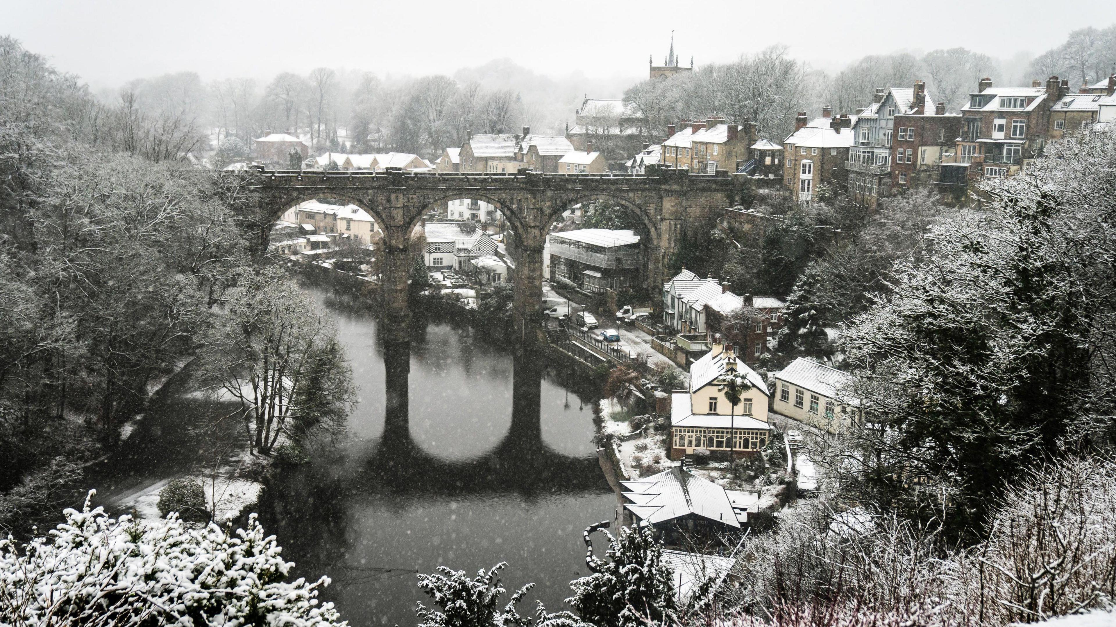 Snow coats rooftops and the viaduct in Knaresborough on a wintry day.