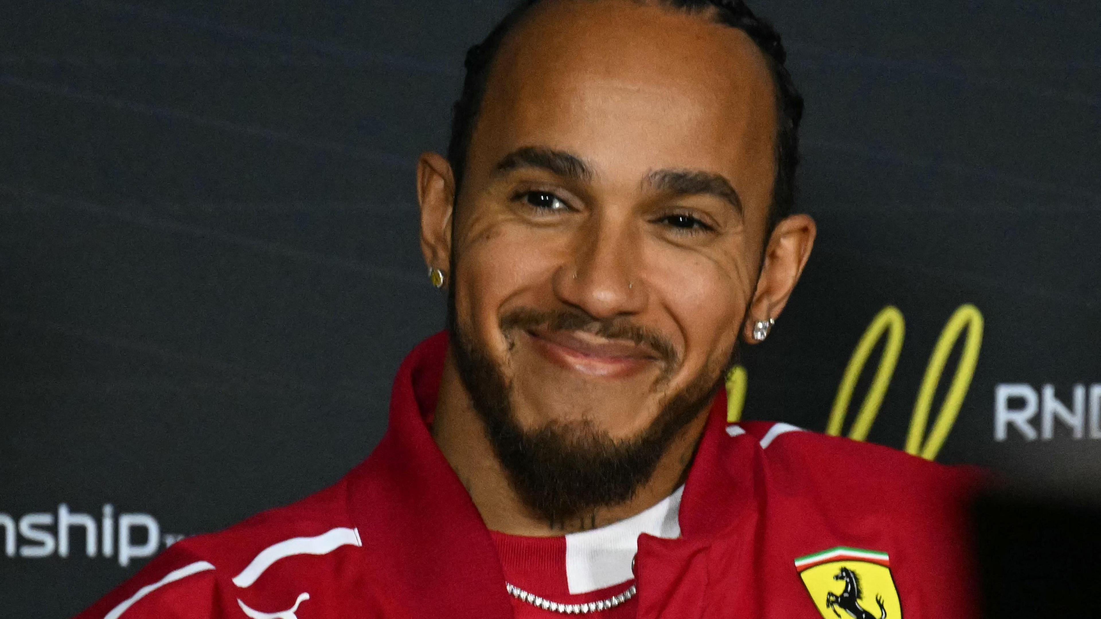 Lewis Hamilton smiling while wearing a Ferrari jacket during the drivers' press conference before the Australian Grand Prix