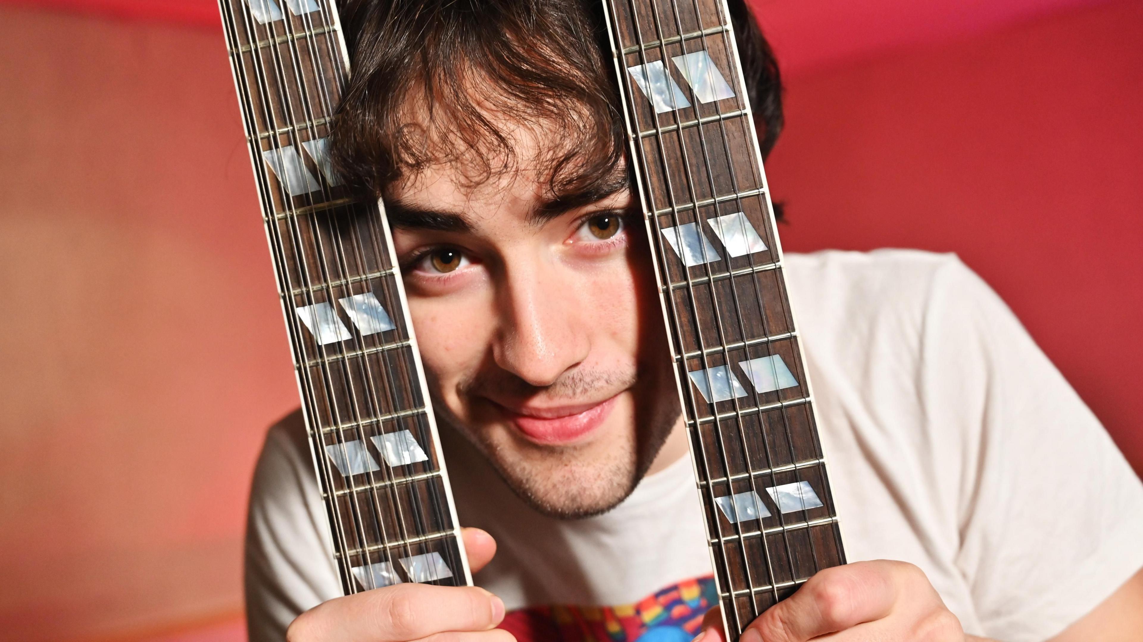 Alfie Templeman smiling between two guitar necks