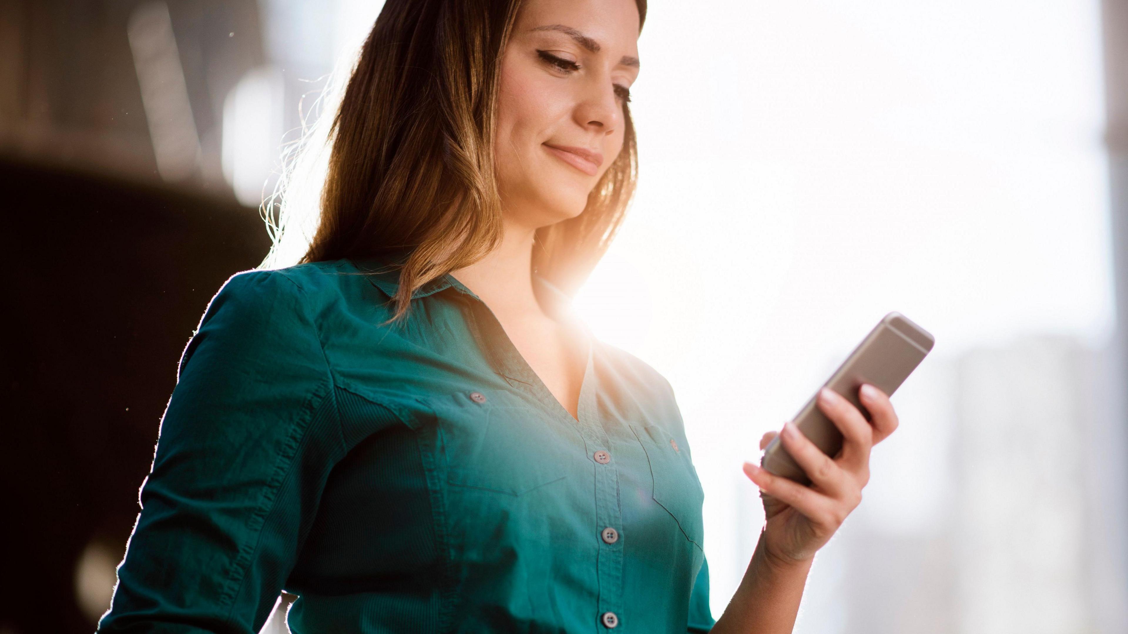 A woman in a green top using her smartphone