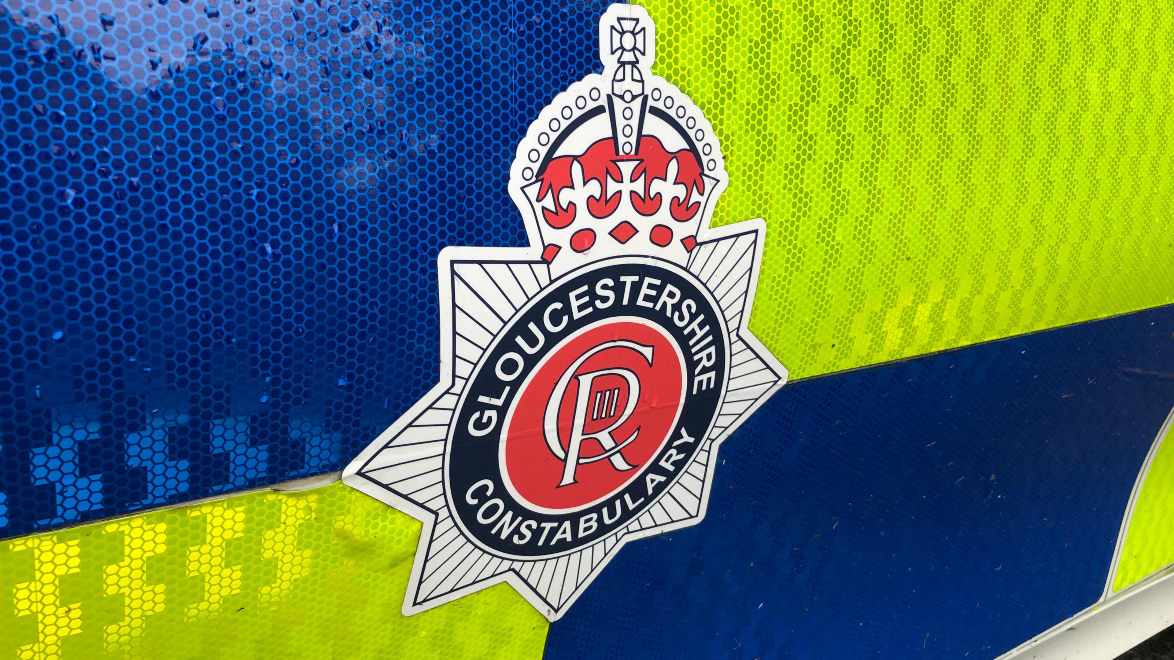 A close up of the Gloucestershire Constabulary crest on the side of a police car.