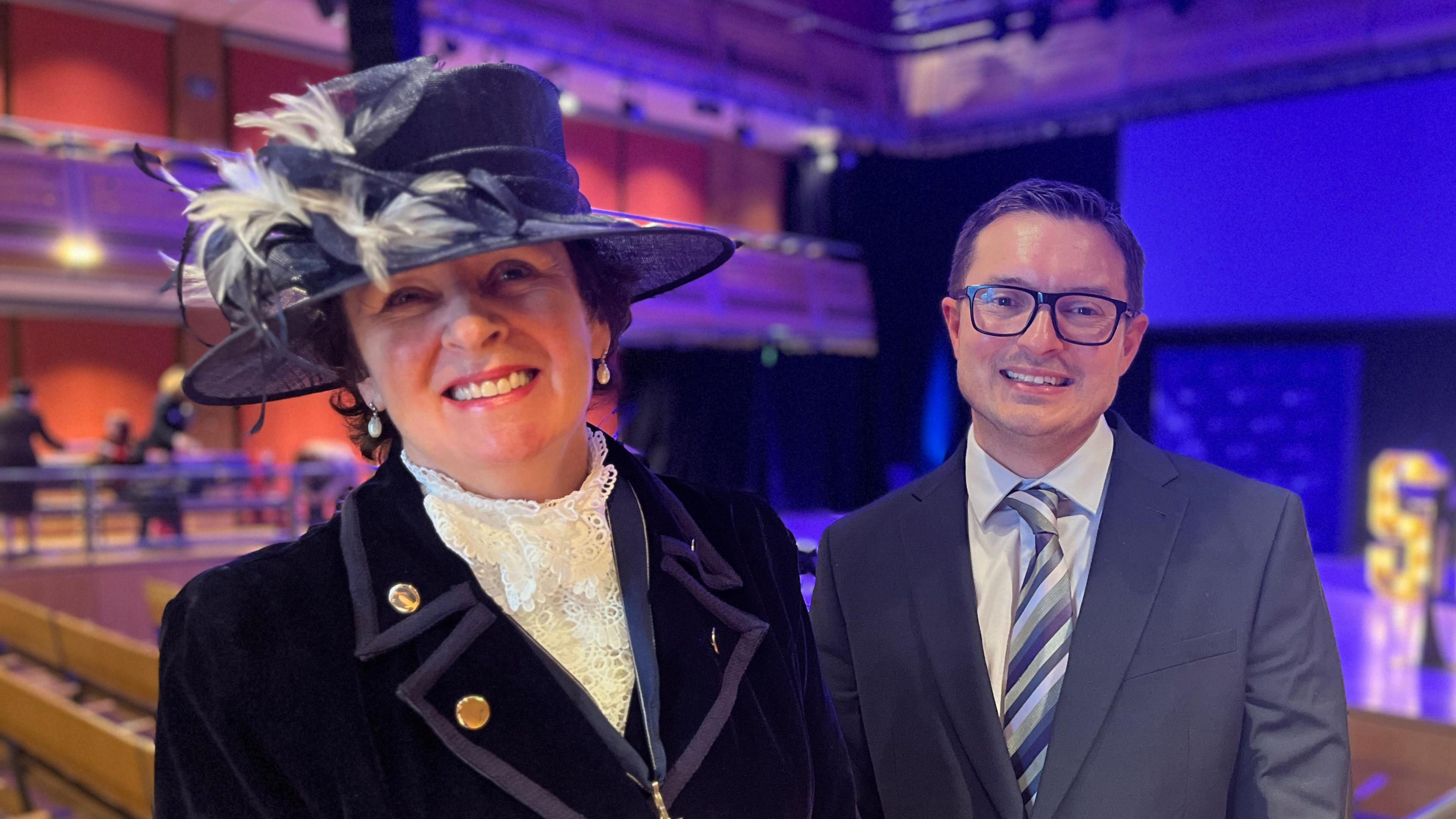 Previous High Sheriff Yvonne Gilchrist-Mason, wearing the formal high sheriff pendant with Gavin Stone standing in front of the stage at the Apex venue in Bury St Edmunds