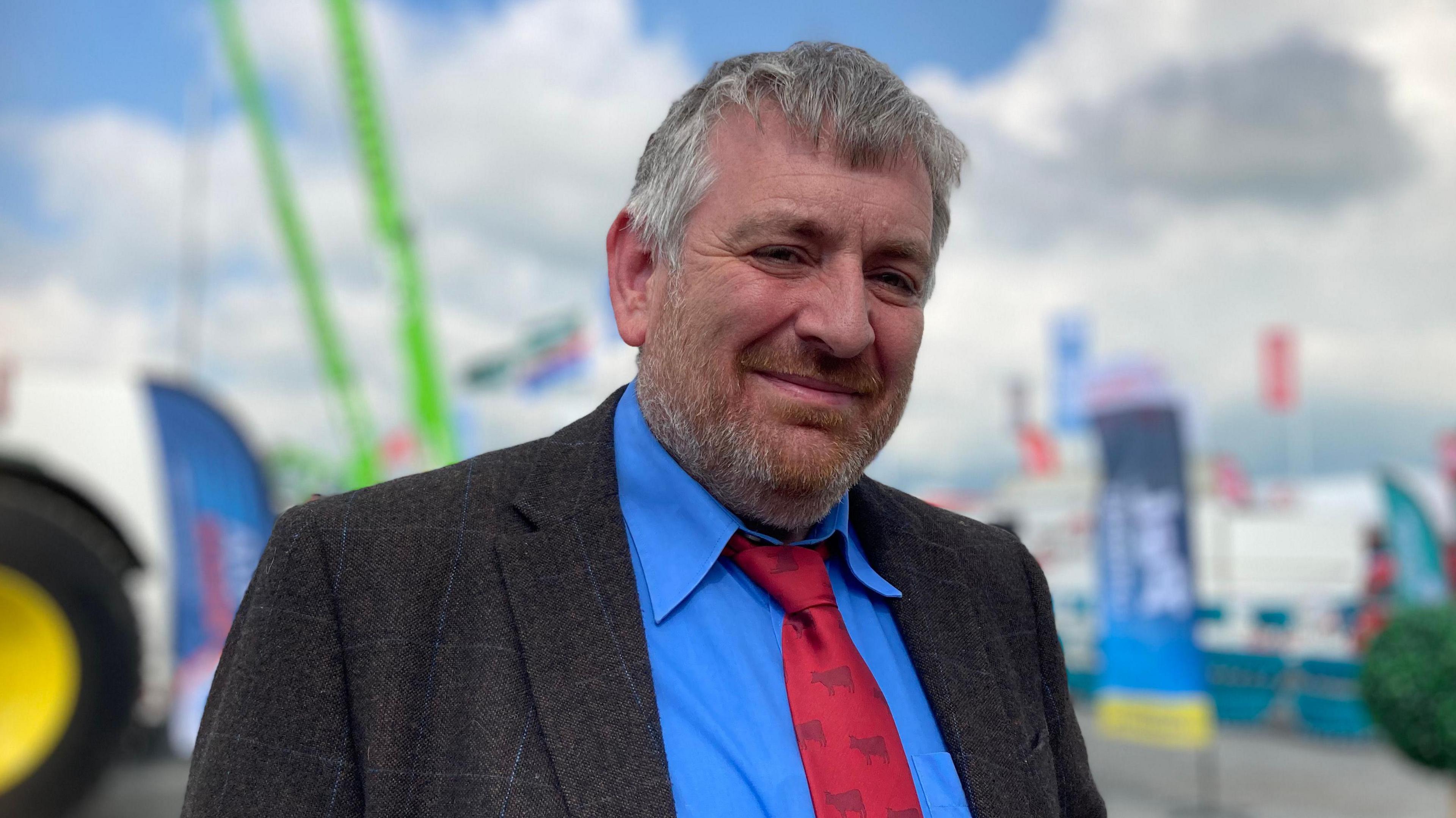 County Down farmer Damien Tumelty in focus with tractors and signage in the blurred backaground