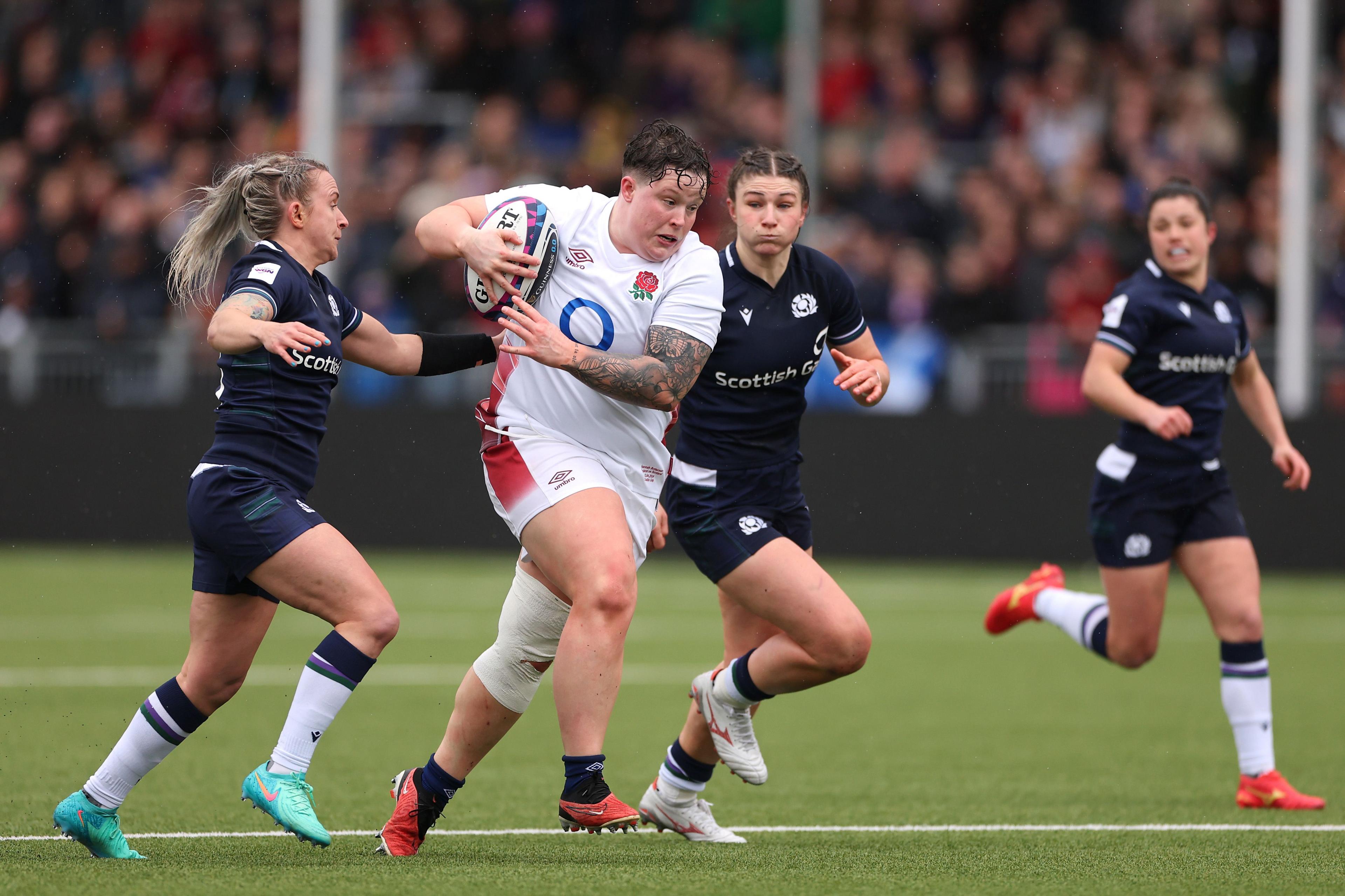 Hannah Botterman charging through a tackle in a white England kit against Scotland during the Women's Six Nations 