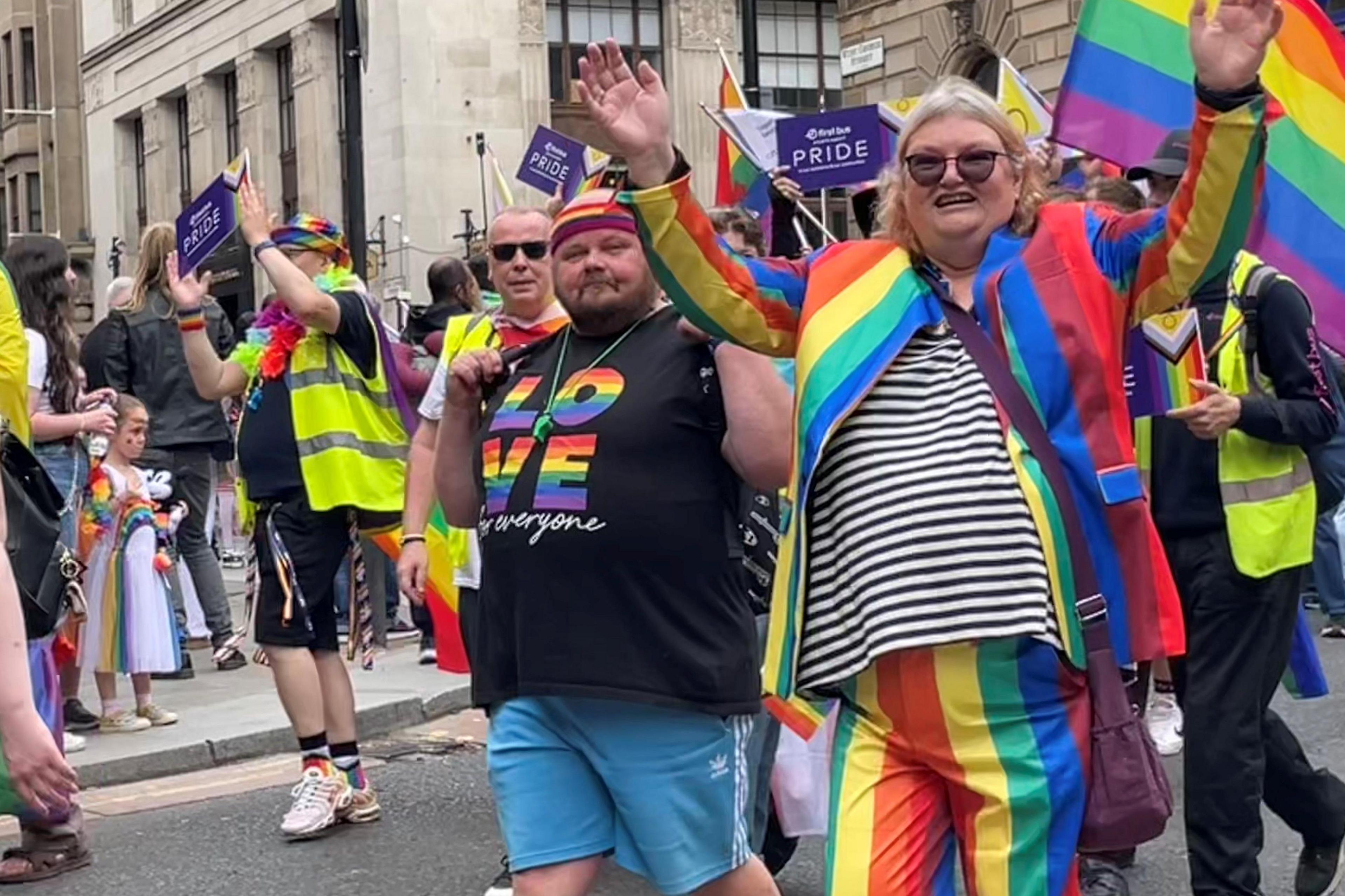 Pride marchers in Glasgow carrying banners and wearing colourful clothes