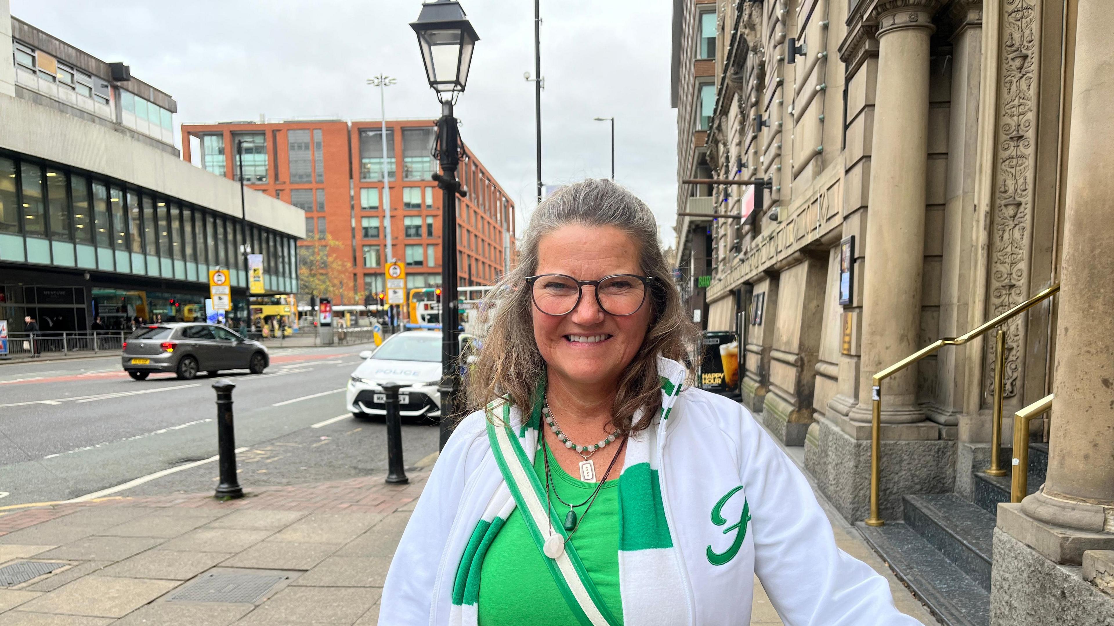 Gittan Norder, wearing a green-and-white Hammarby scarf and white jacket, poses for a photograph in Manchester city centre.