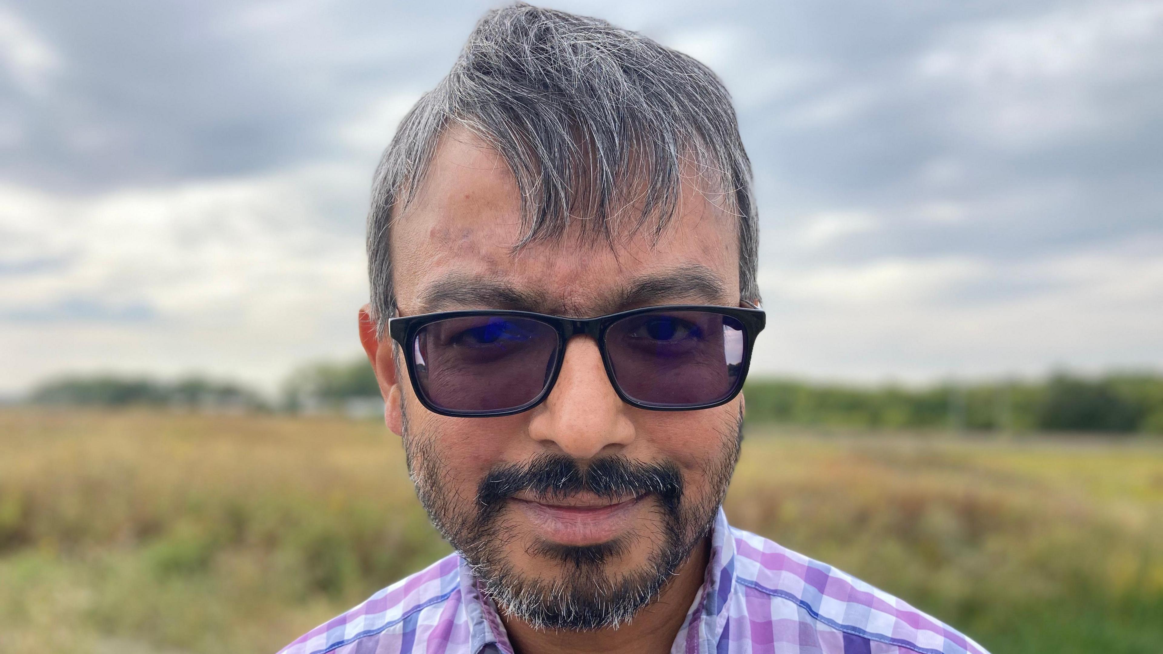 Saqhib Ali, wearing sunglasses, and a checked shirt, in a field in Wixam's, Bedfordshire