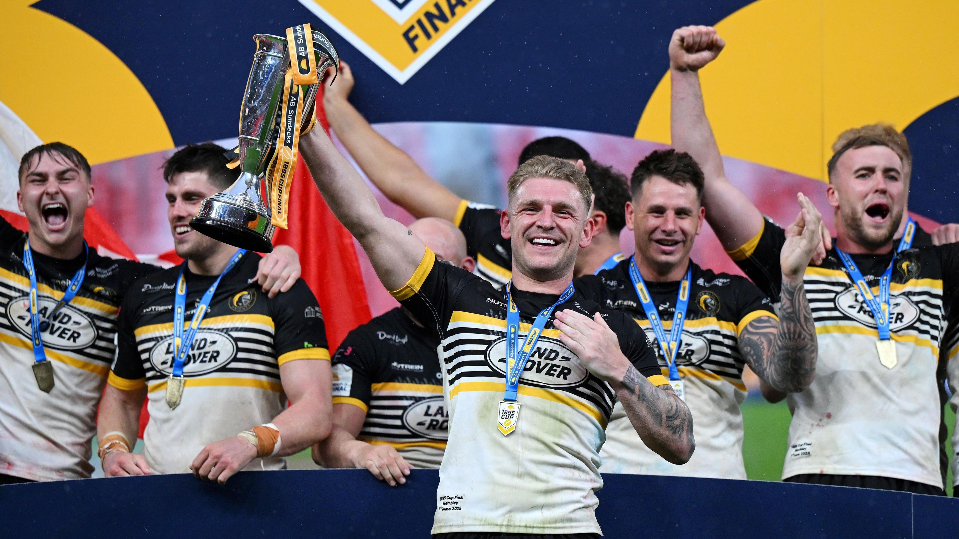 Liam Harris lifting the 1895 Cup alongside team-mates