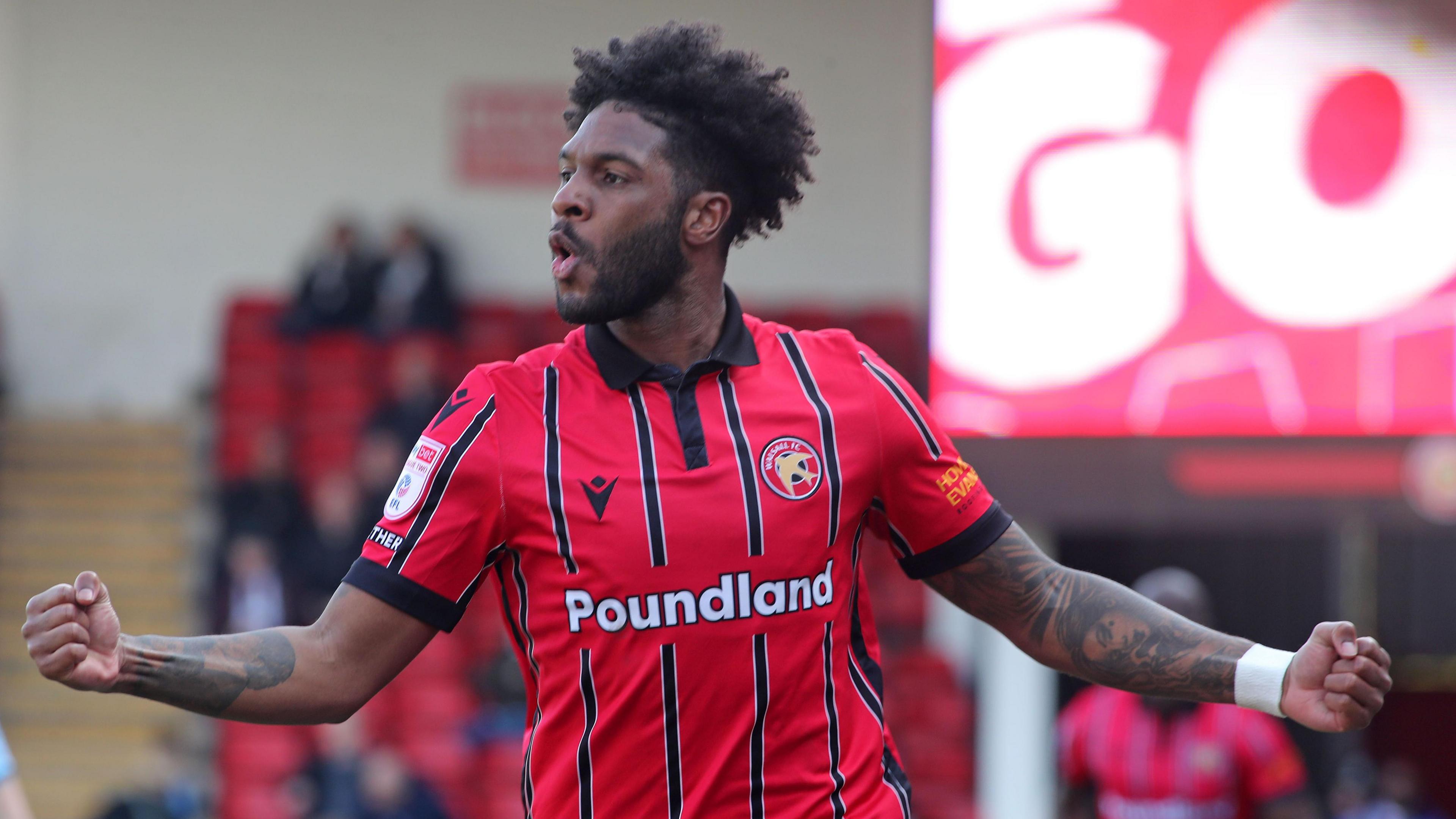 Ellis Harrison holds both his arms out as he runs in celebration after scoring a goal for Walsall