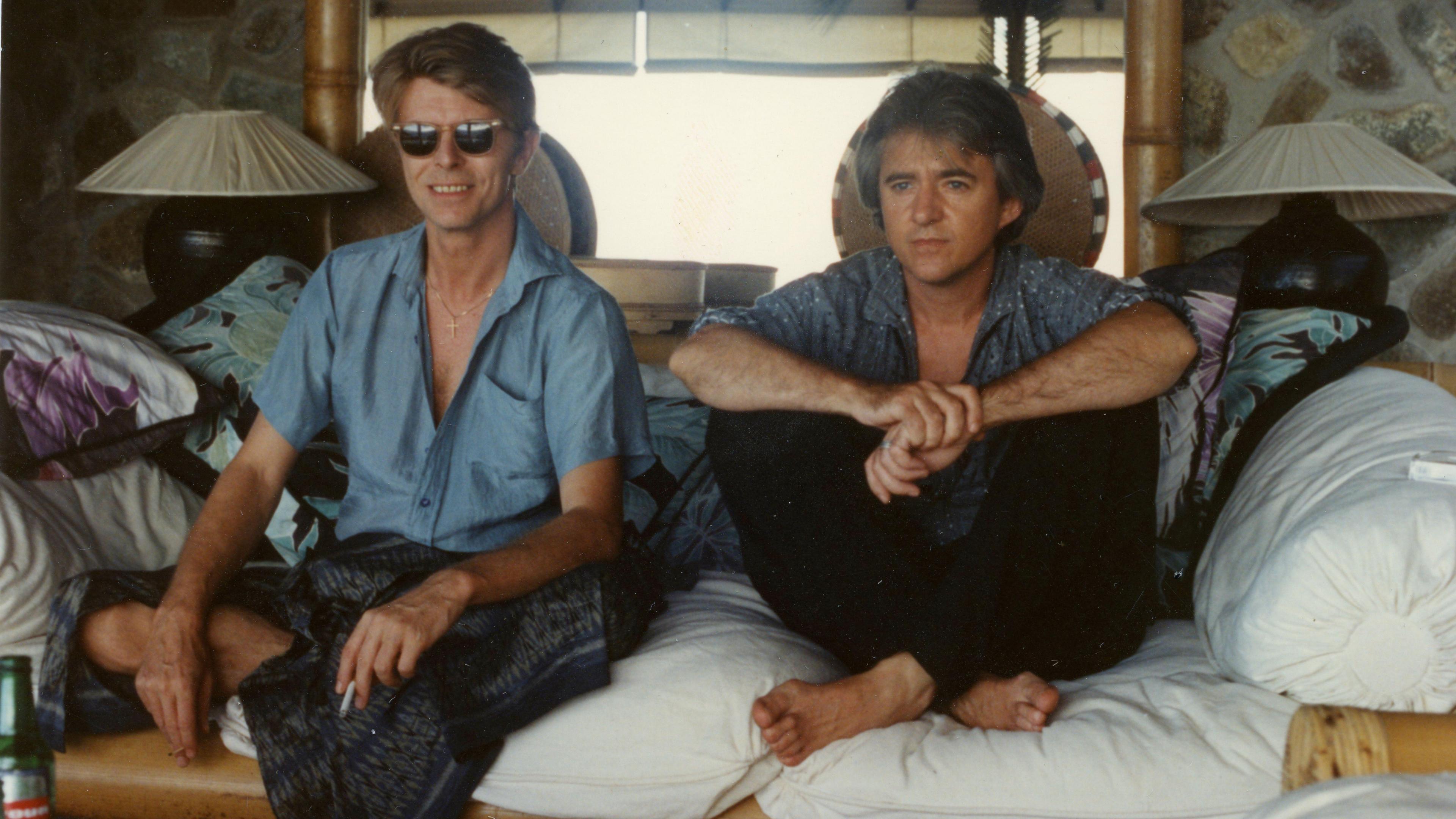 David Bowie and George Underwood sitting on a sofa in Mustique