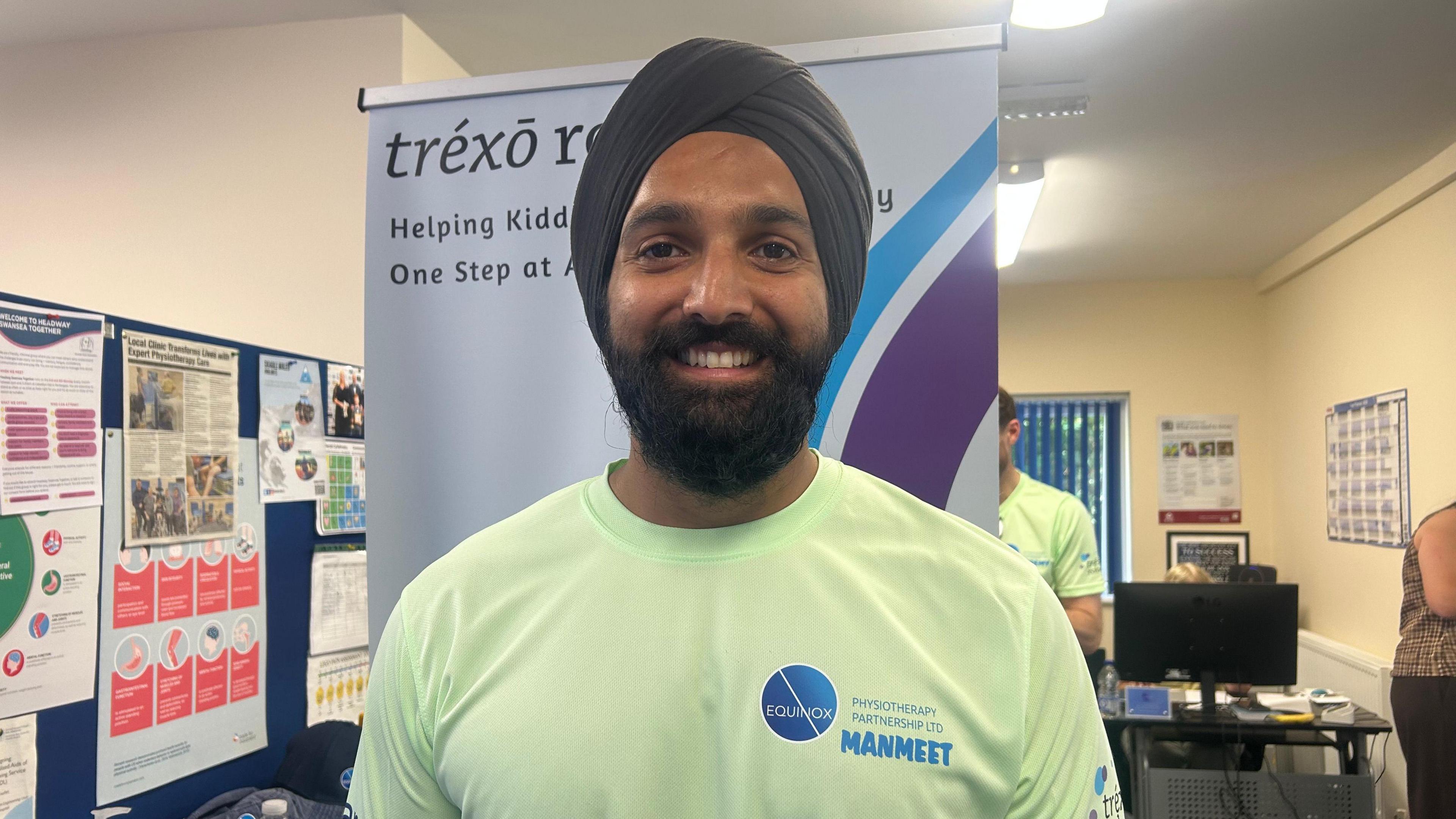 Manmeet Maggu in a green Equinox t-shirt. He wears a black turban, and has a dark beard