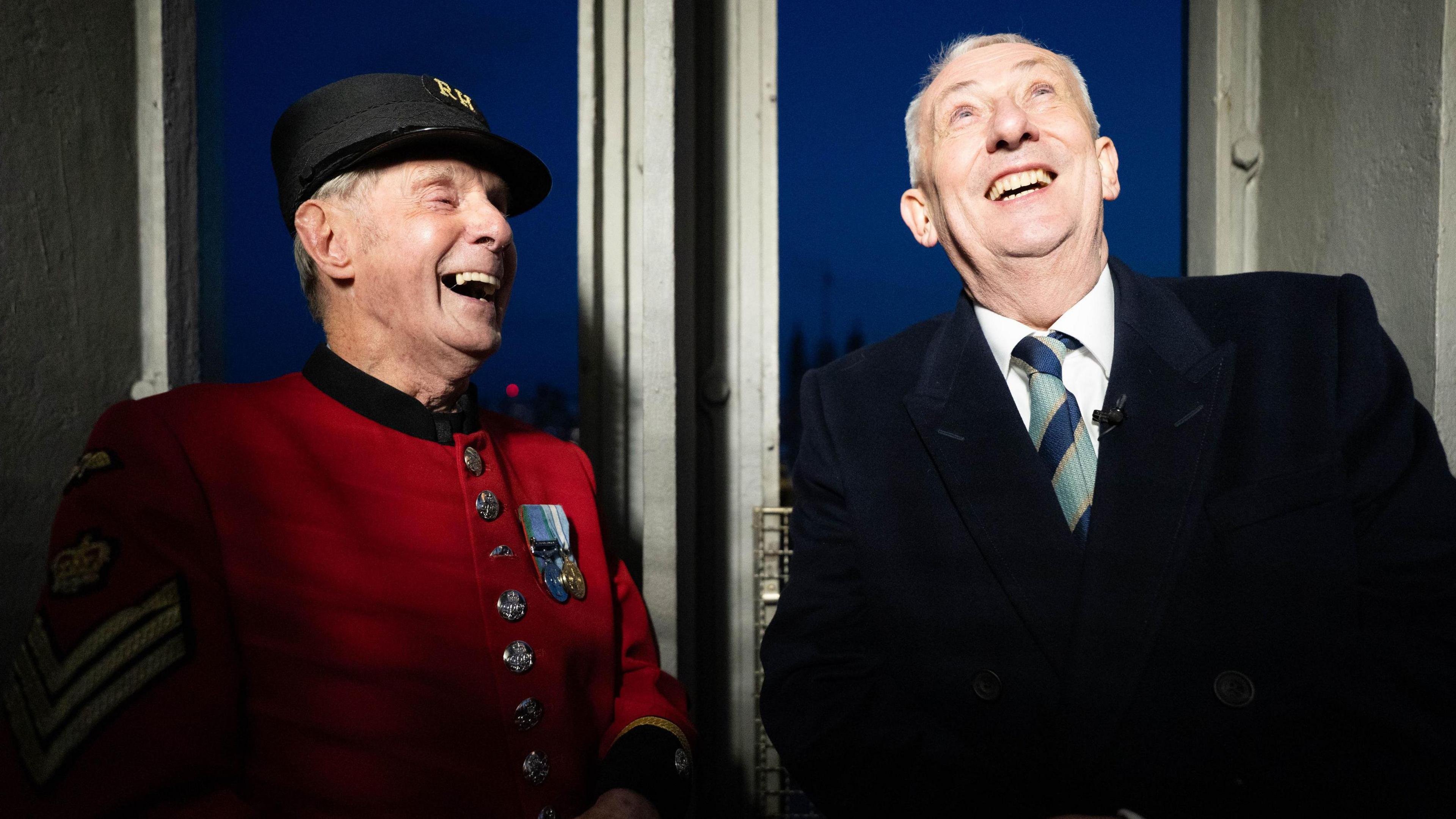 Tony Hunt, wearing the red uniform of the Chelsea pensioners stands next to Speaker Sir Lindsay Hoyle. Both men are laughing