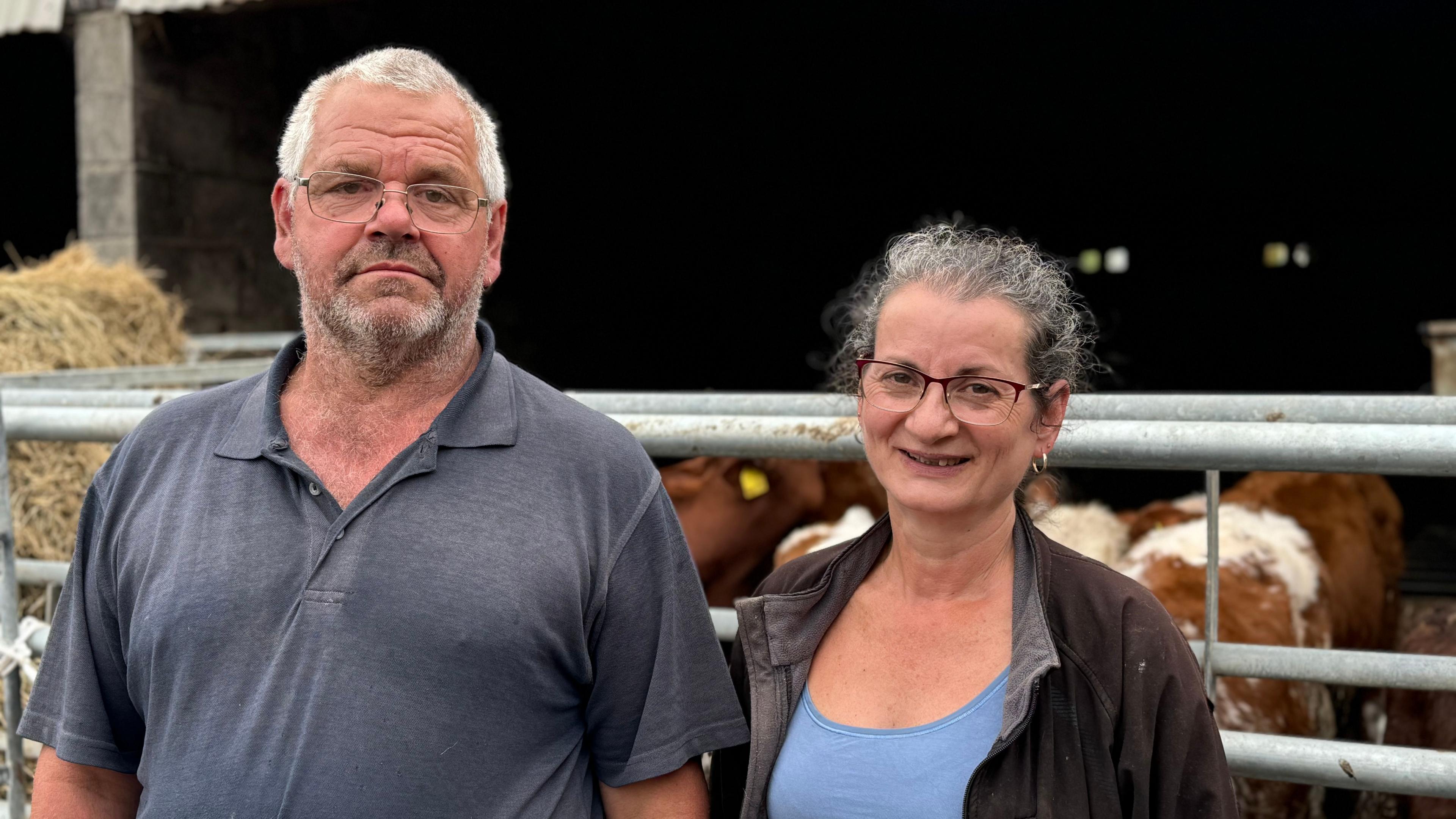 Farmer couple stood in front of their herd