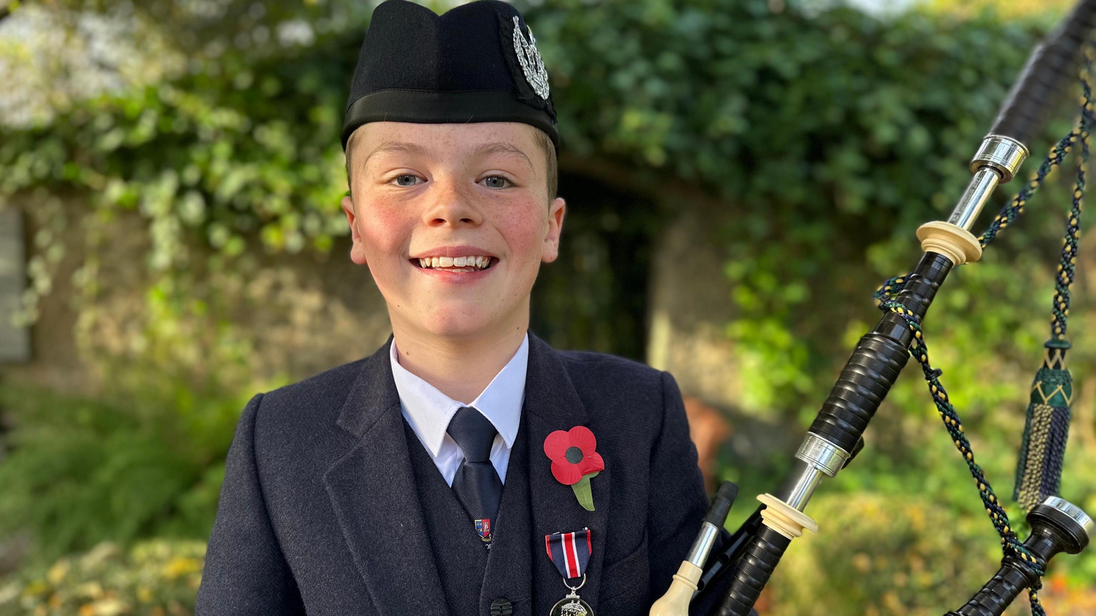 Andrew Fagan, 11, in Highland dress and wearing a poppy and a medal for playing in the people's procession on his lapel, holds his bagpipes in the gardens of the Gordon Highlanders Museum.