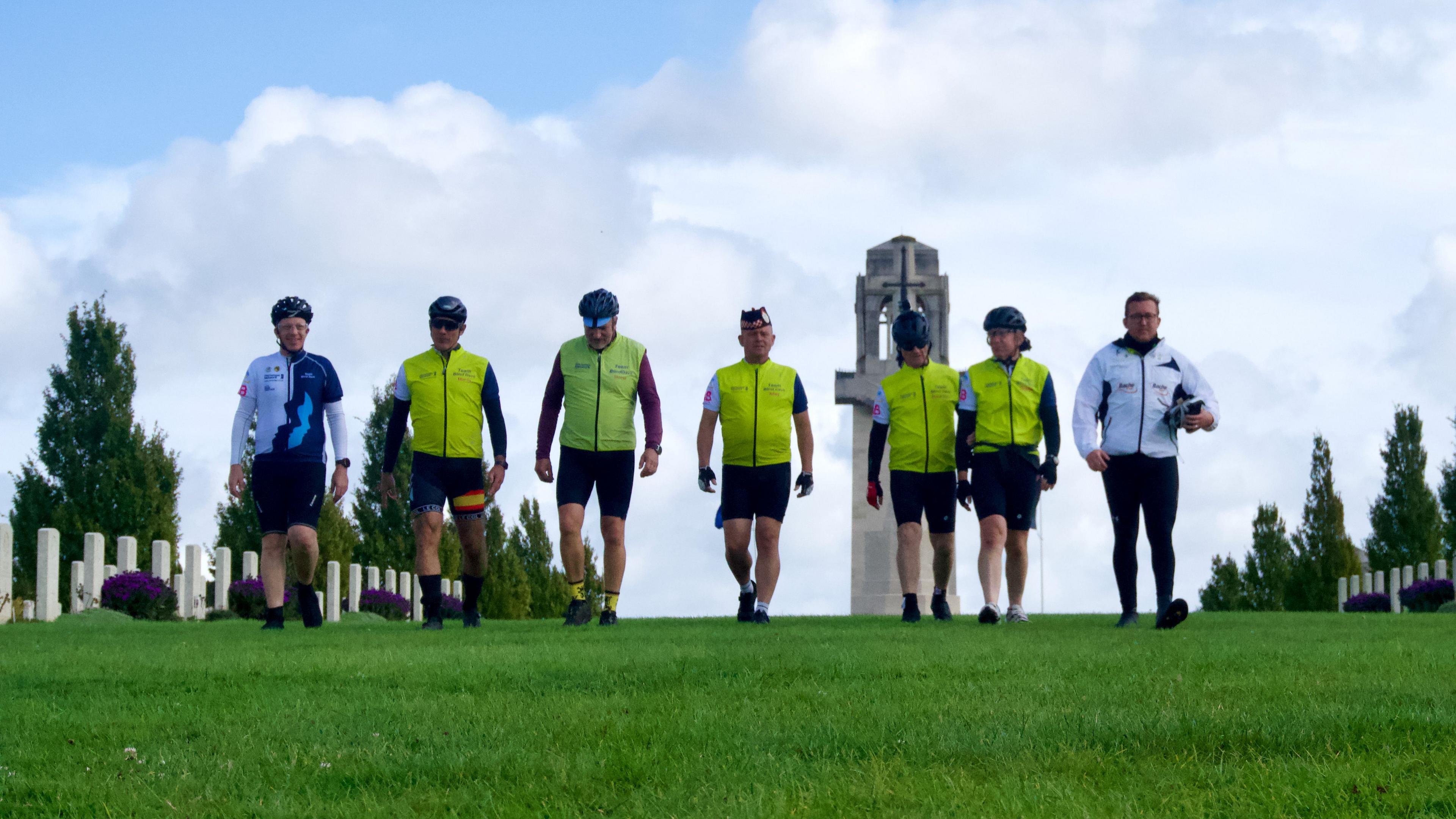 Seven cyclists walking through a war cemetery in France