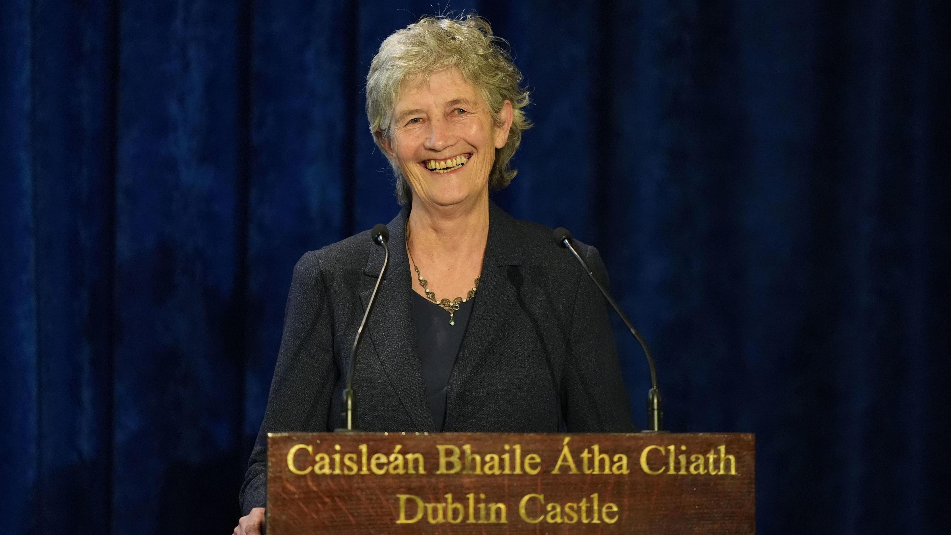 Catherine Connolly wears a dark coloured blazer. She has short cropped grey hair and is smiling. 