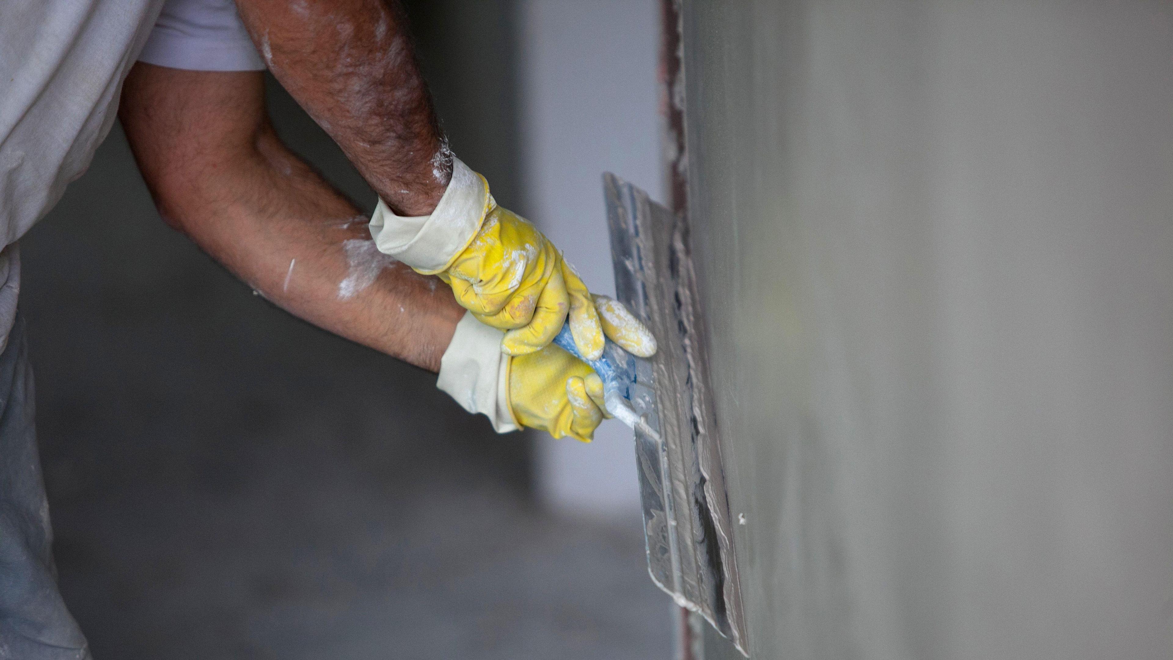 A generic shot of a plasterer plastering a wall using a large trowel