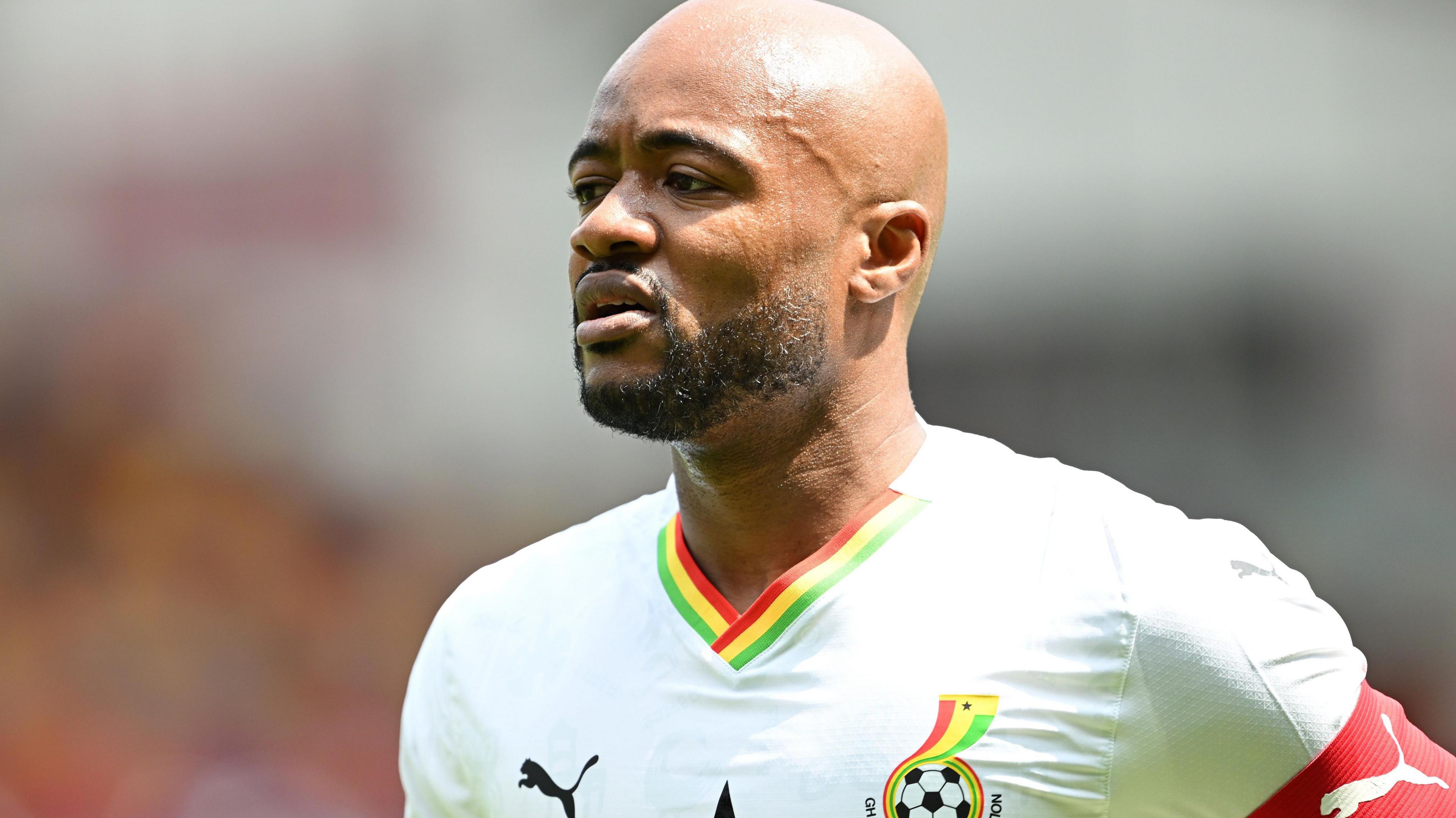Jordan Ayew wears a white Ghana shirt and a red captain's armband