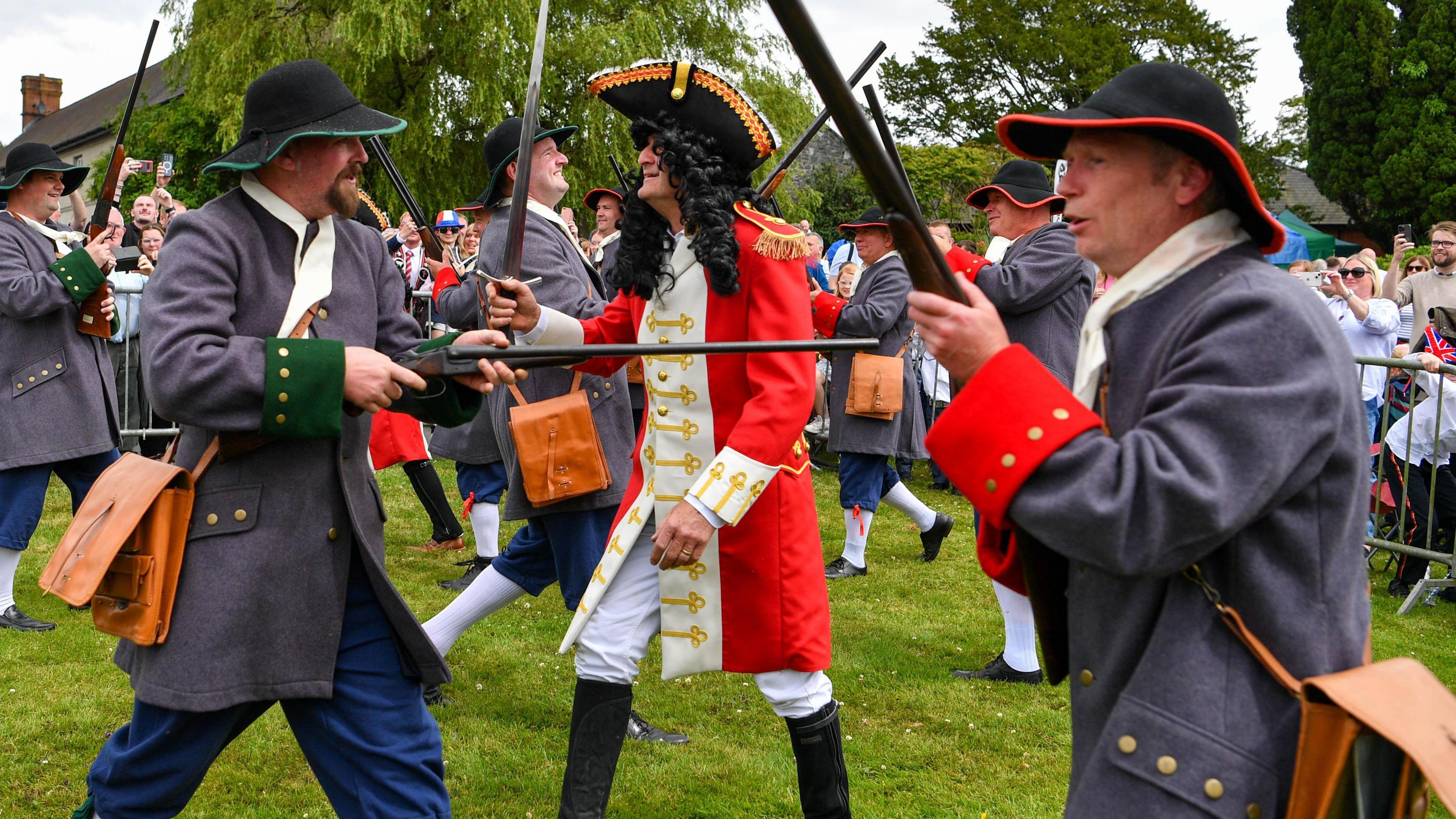 Men in historical costumes point fake weapons at each other as they take part in the Sham Fight in Scarva