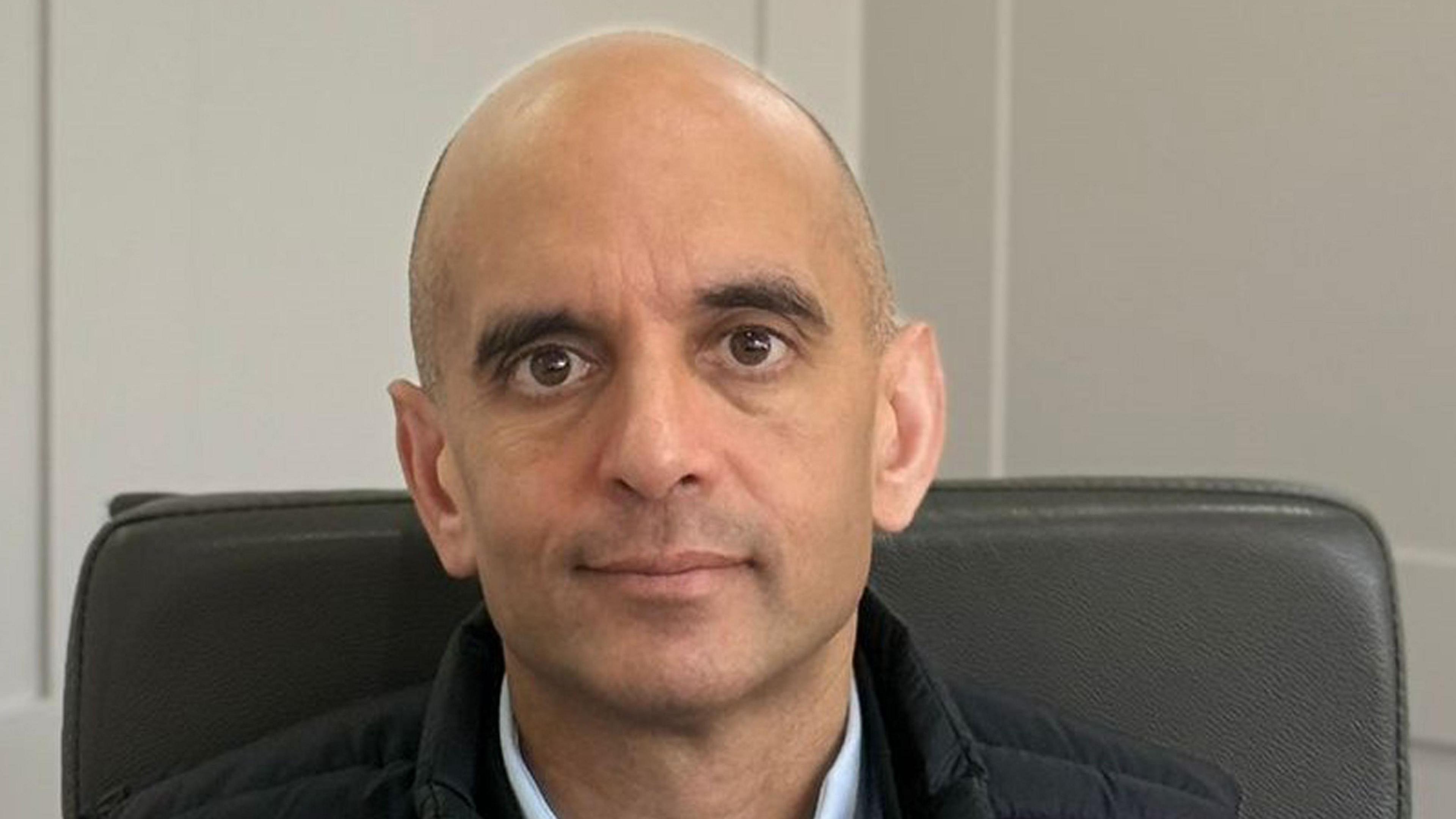 A headshot of Nick Lees - a man with no hair and brown eyes looks directly into the camera.