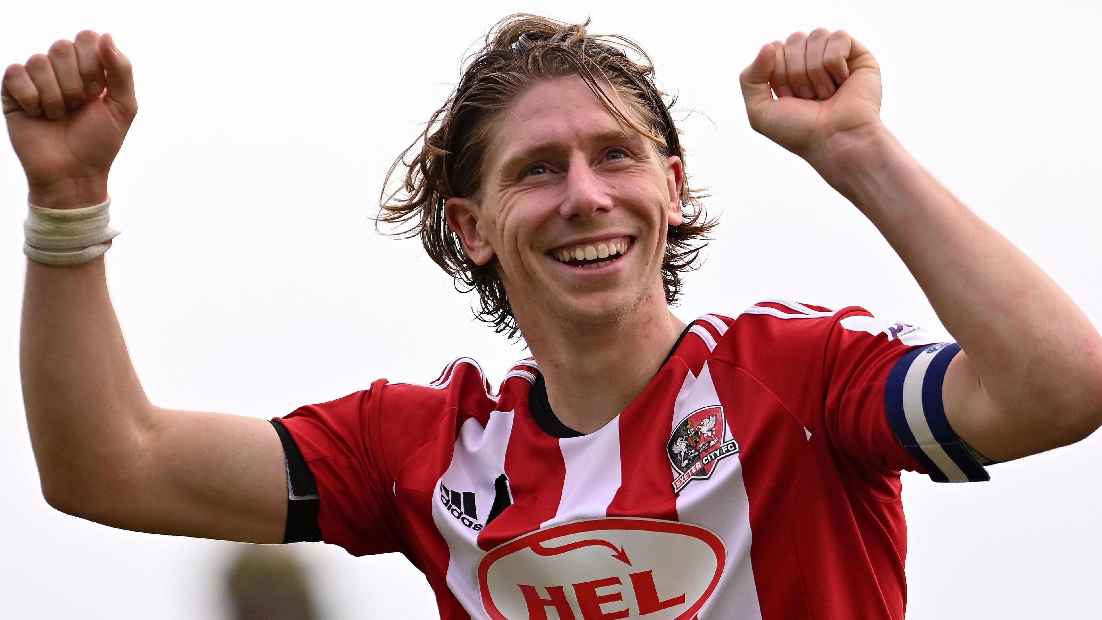 Alex Hartridge wearing a red and white-striped Exeter shirt in action for club.