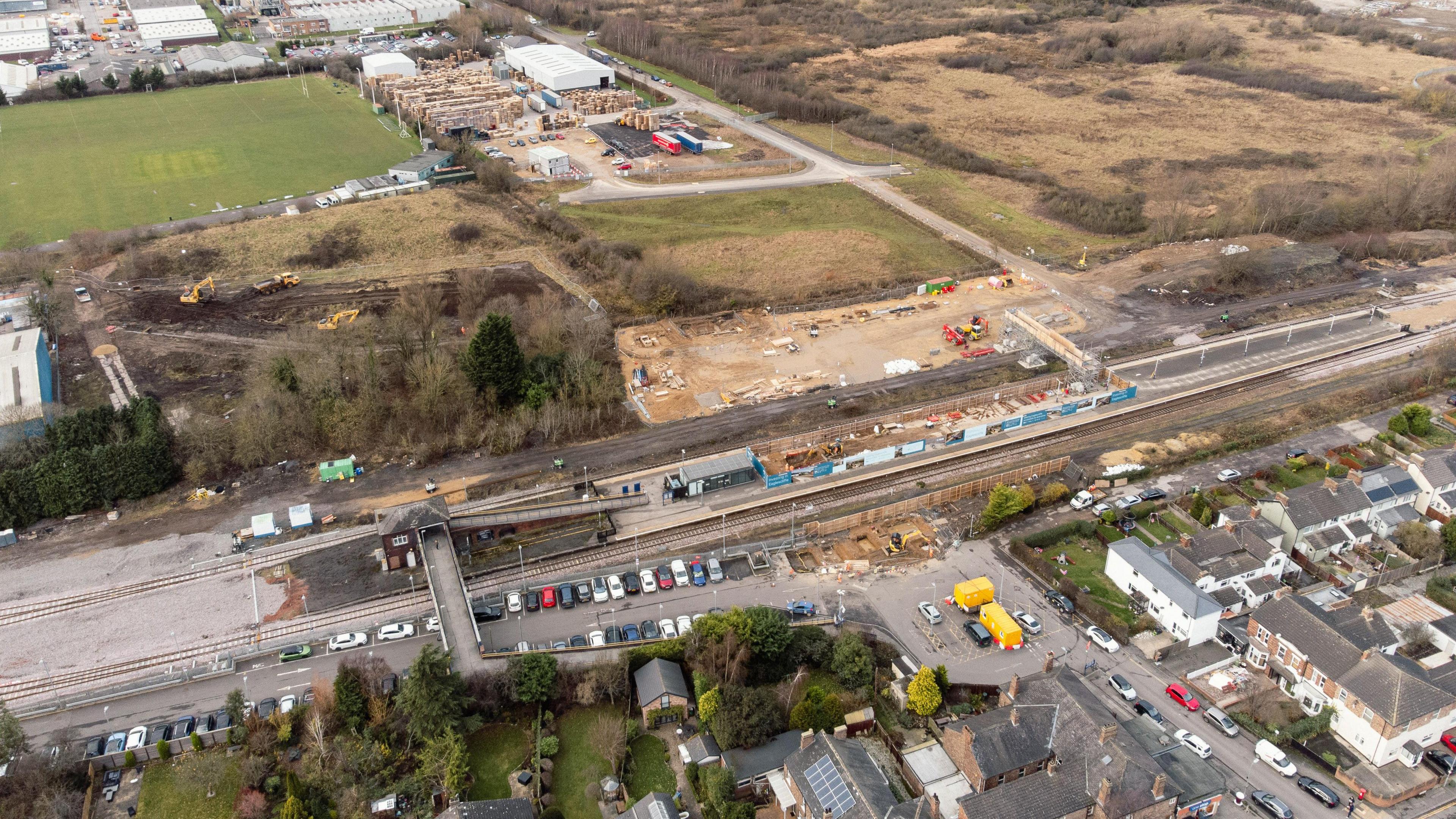 An aerial view of Eaglescliffe station. Cars can be seen parked outside of the station. Construction work can be seen taking place on the island platform. A large building site is present on the far side of the station.