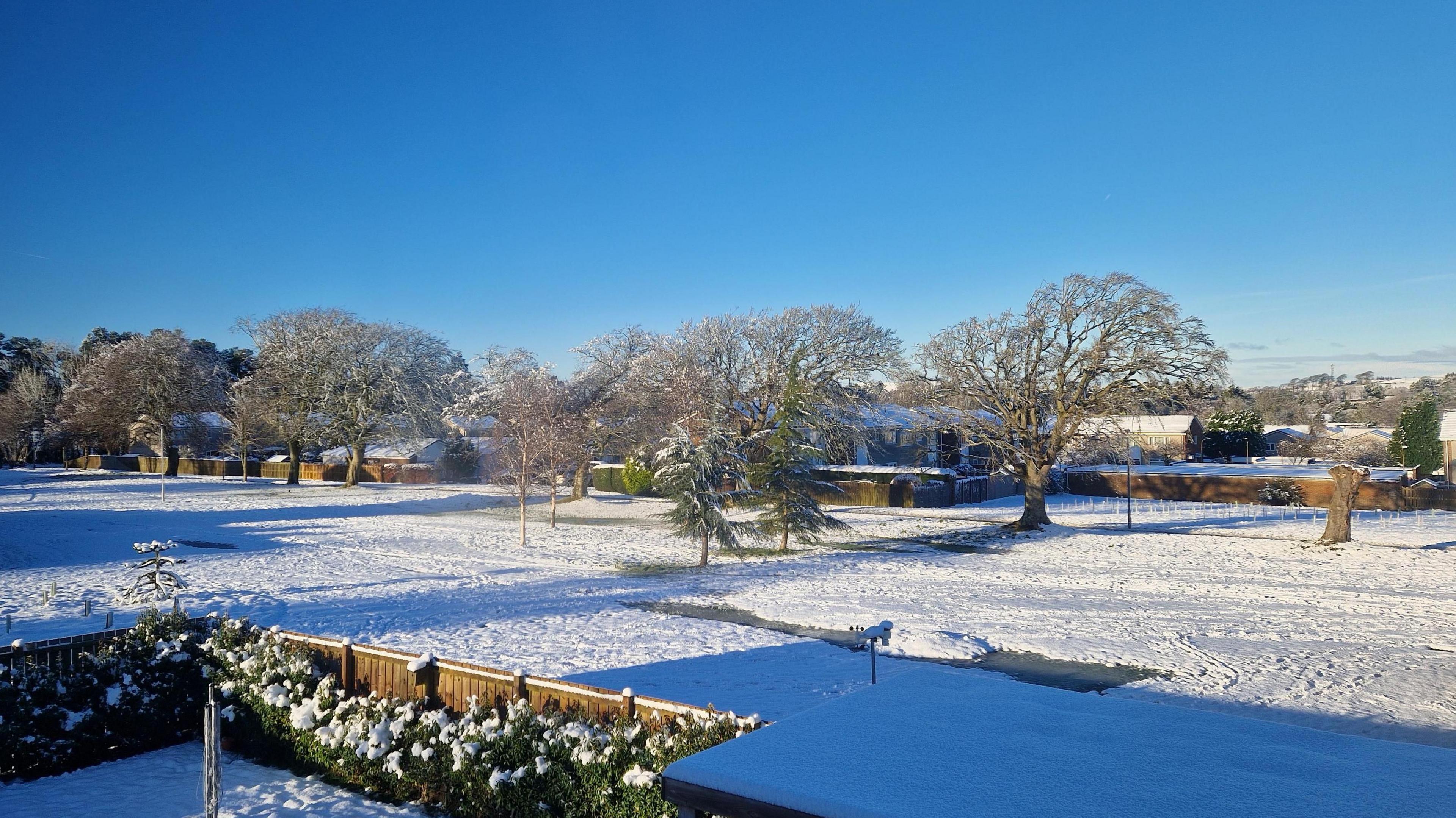 A snowy landscape scene in Edinburgh, Scotland shows a large field blanketed in snow.