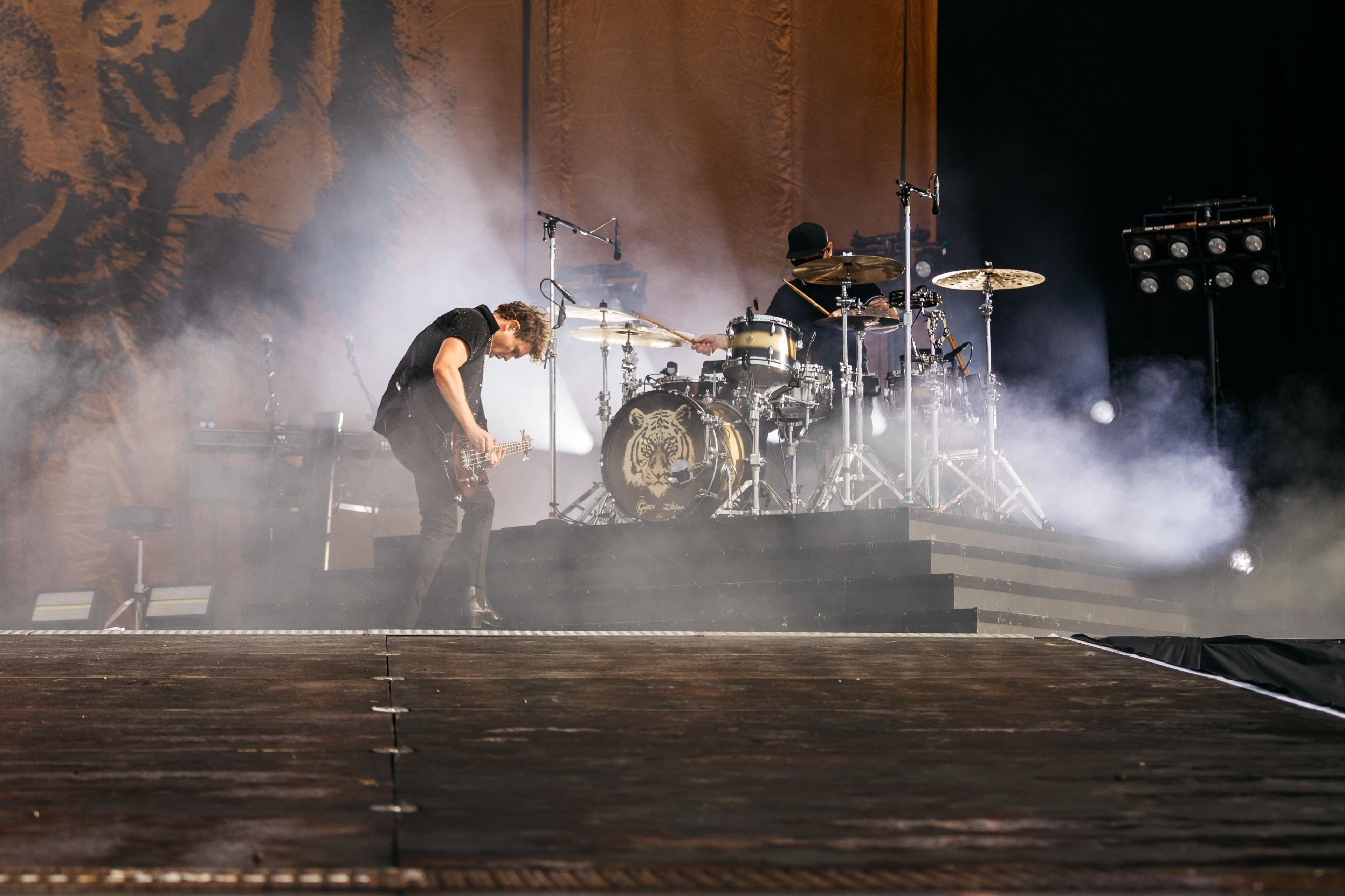 Royal Blood on stage at Download Festival 2024. Mike is on the left playing the guitar and Ben is on the right playing the drums. They are surrounded by smoke.