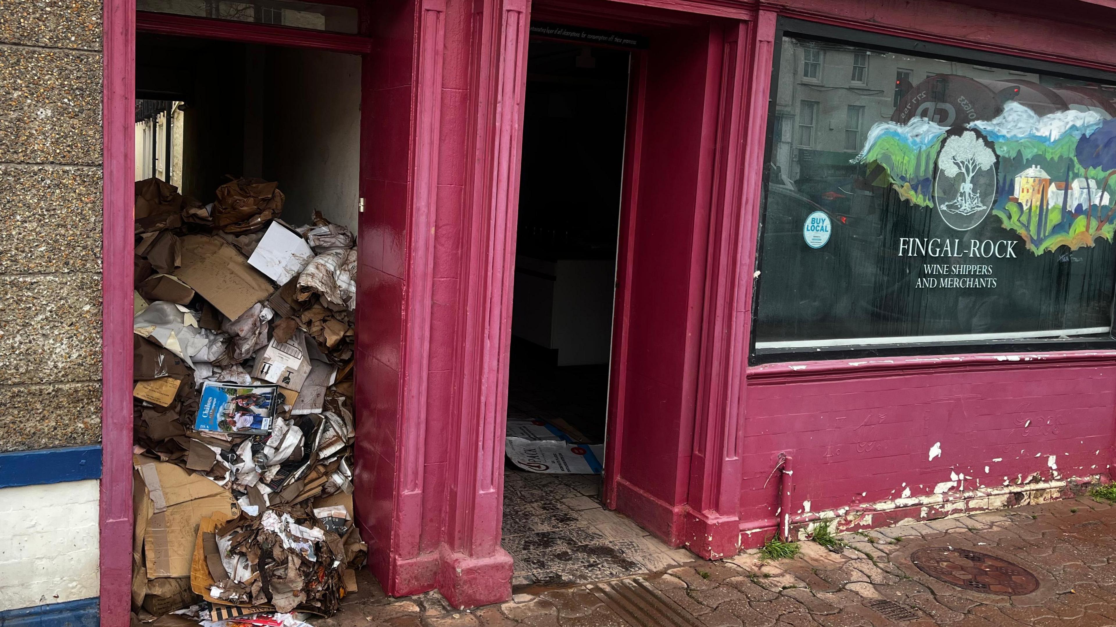 Piles of soaking cardboard block a wine merchants doorway