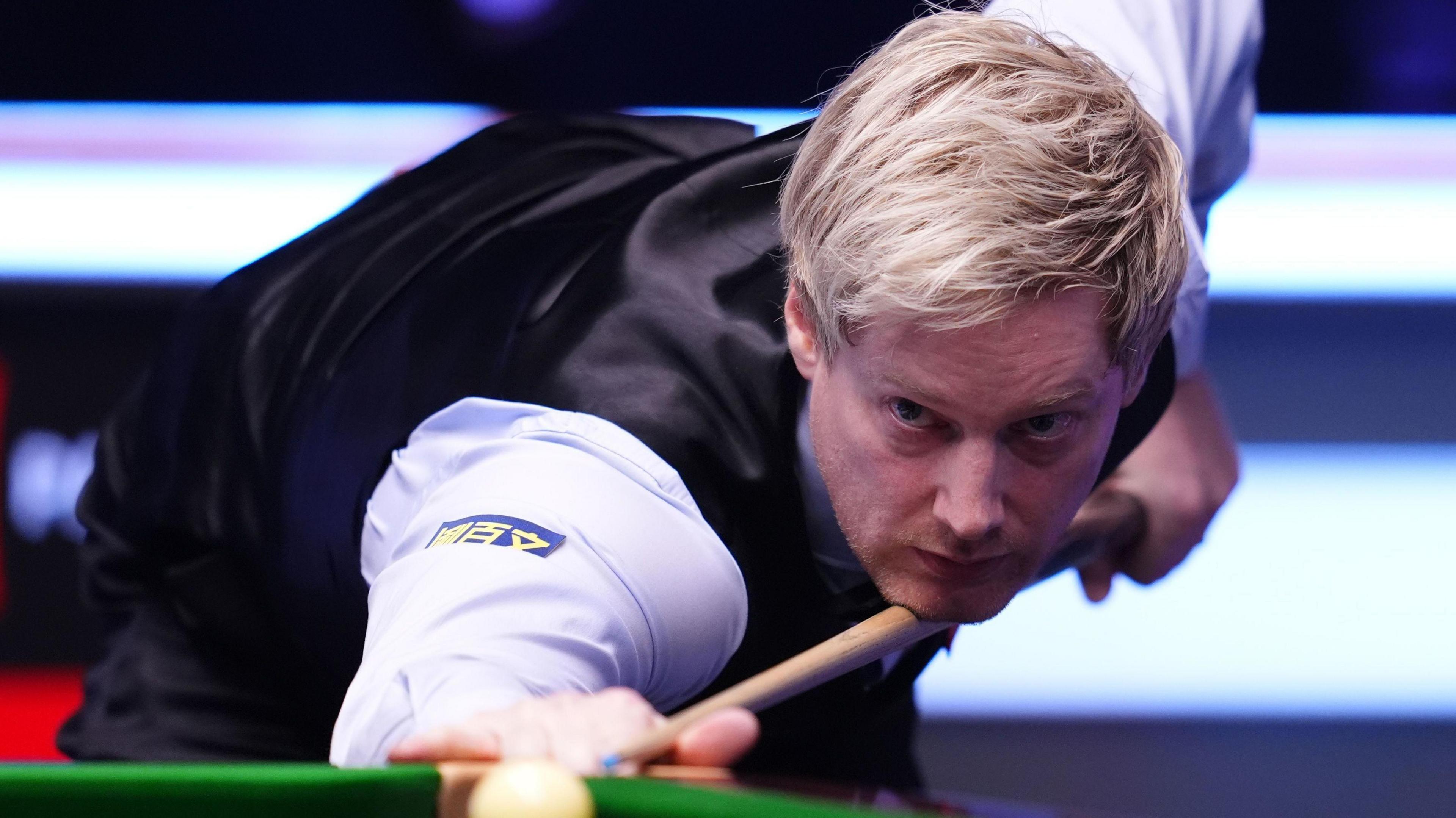 Neil Robertson looks down his snooker cue as he takes aim at the white ball. He has blond hair and is wearing a white shirt under a black waistcoat.