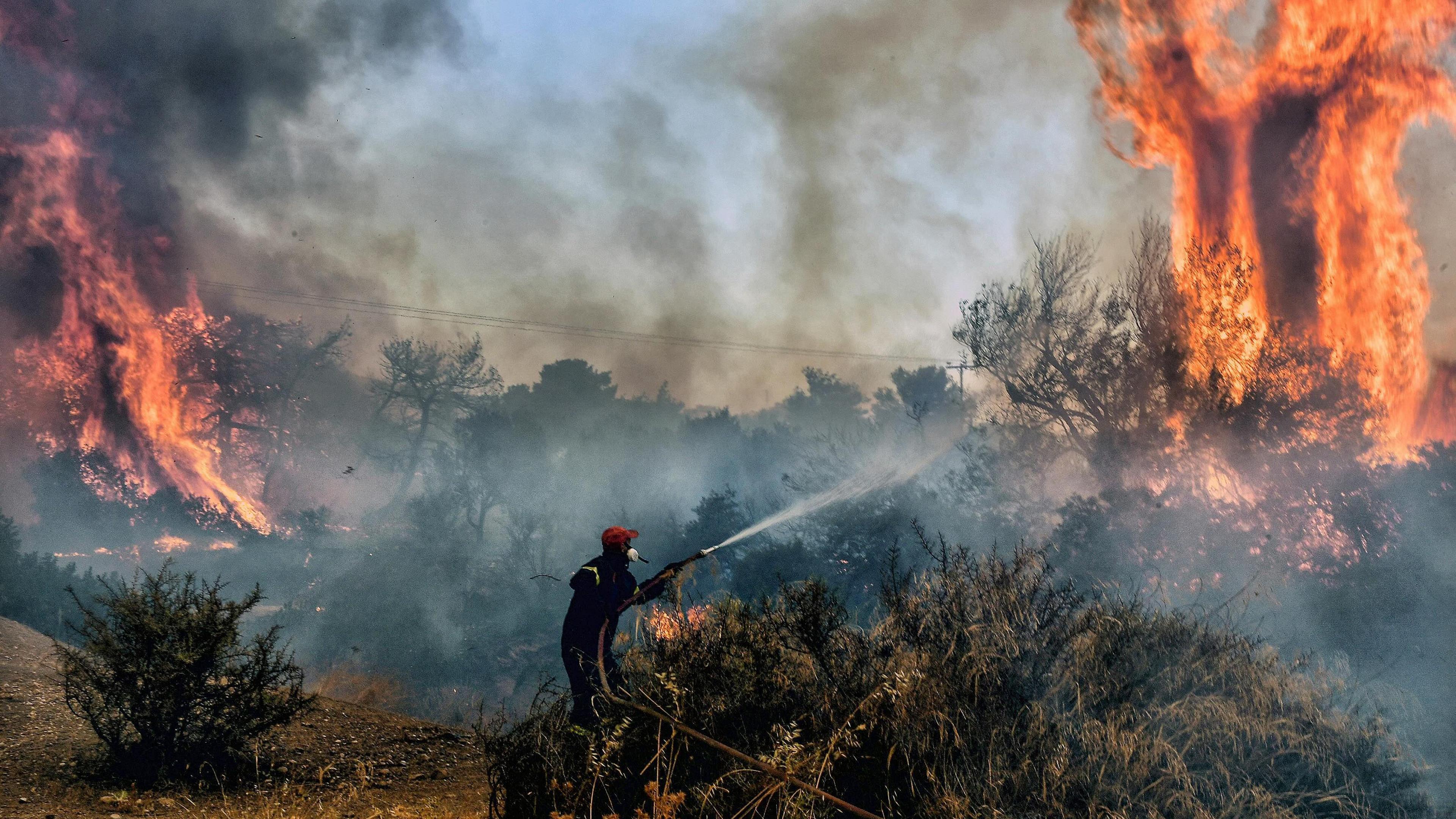 A fireman douses flames on a wildfire at Panorama settlement near Agioi Theodori