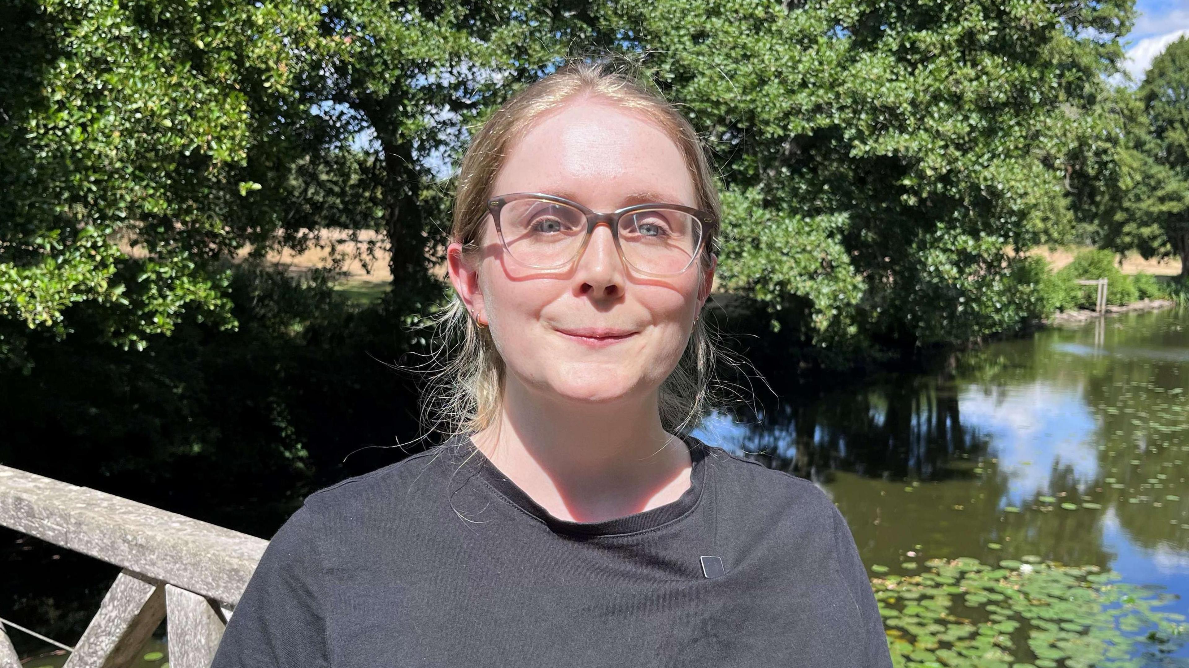 Naomi Collick. She has blonde hair and is wearing a grey T-shirt and spectacles