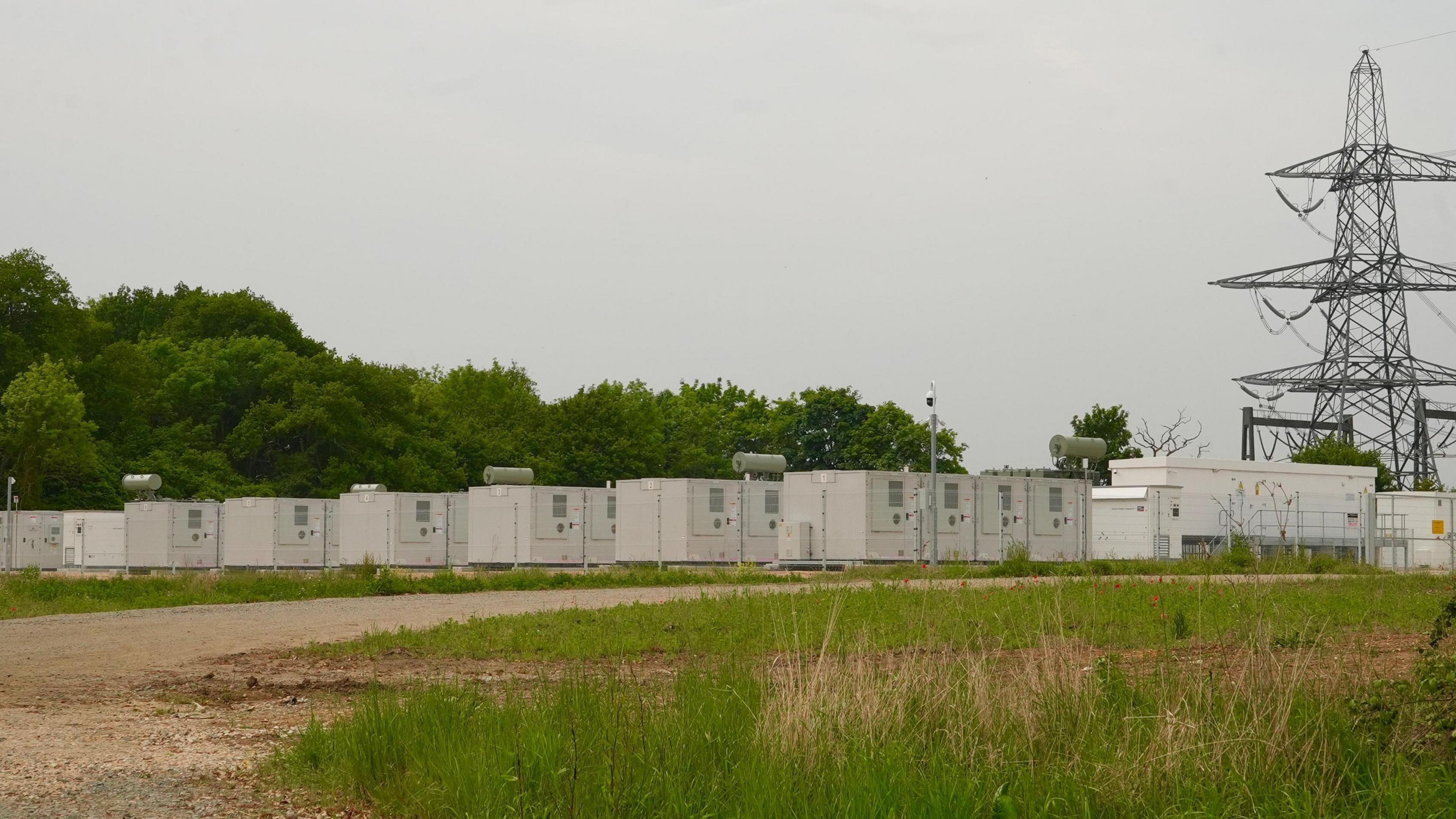 A rural site containing rows of large metal boxes that resemble shipping containers.