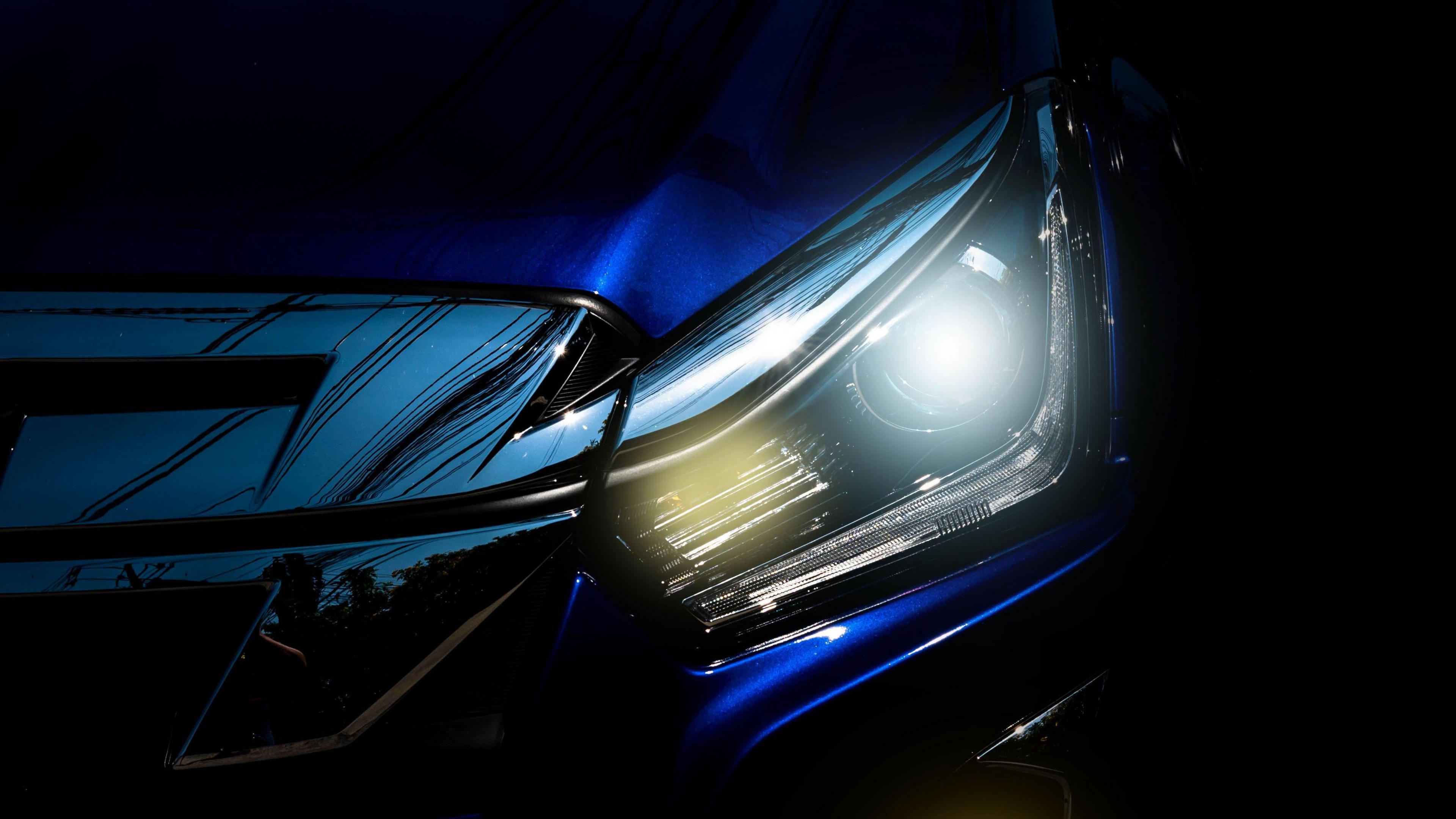 Close-up of an LED headlight shining in the dark with a blue-white glow