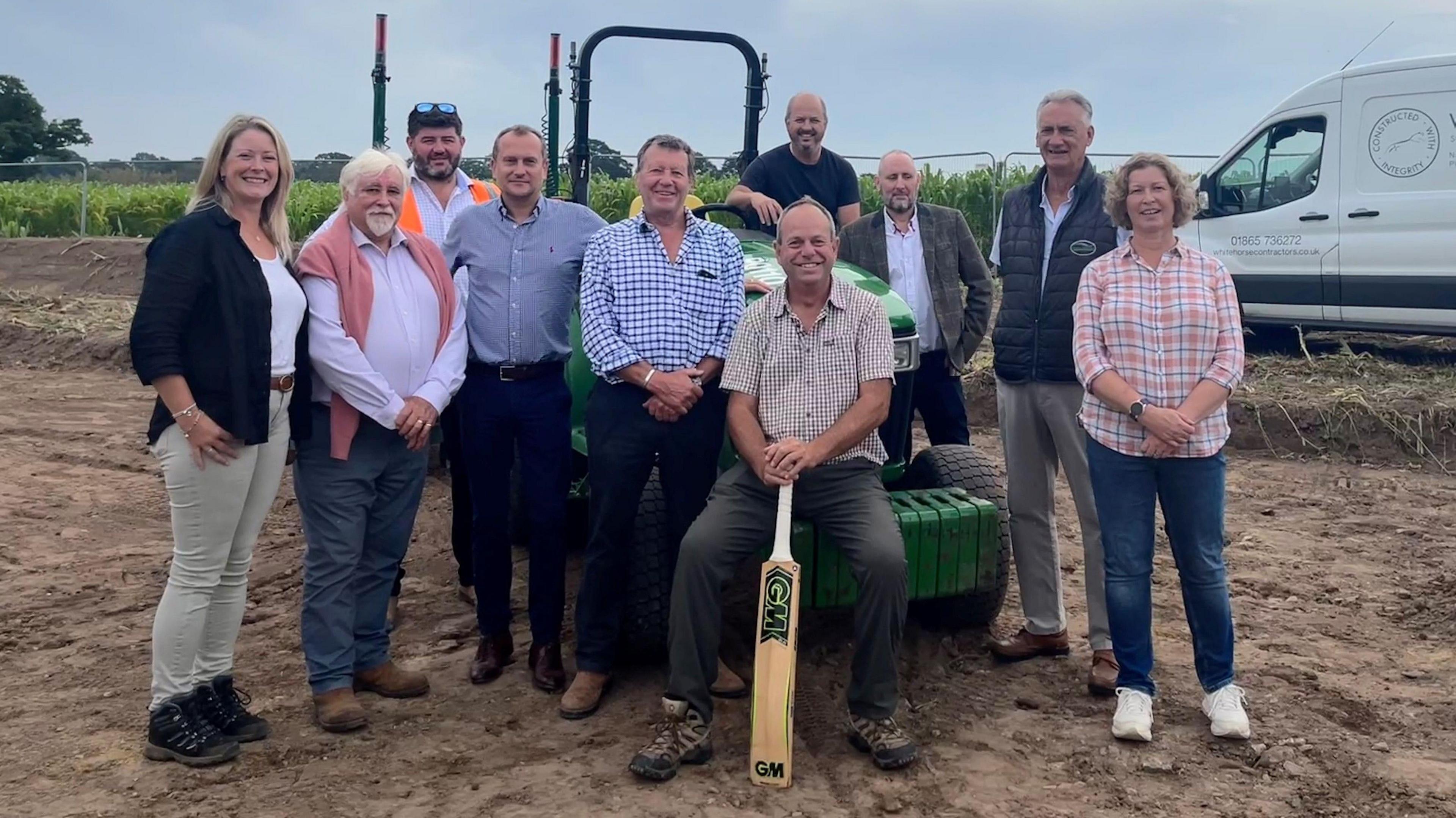 Cullompton cricket club chairman Richard Stephenson holding a cricket bat at centre of group of people at the new cricket club site