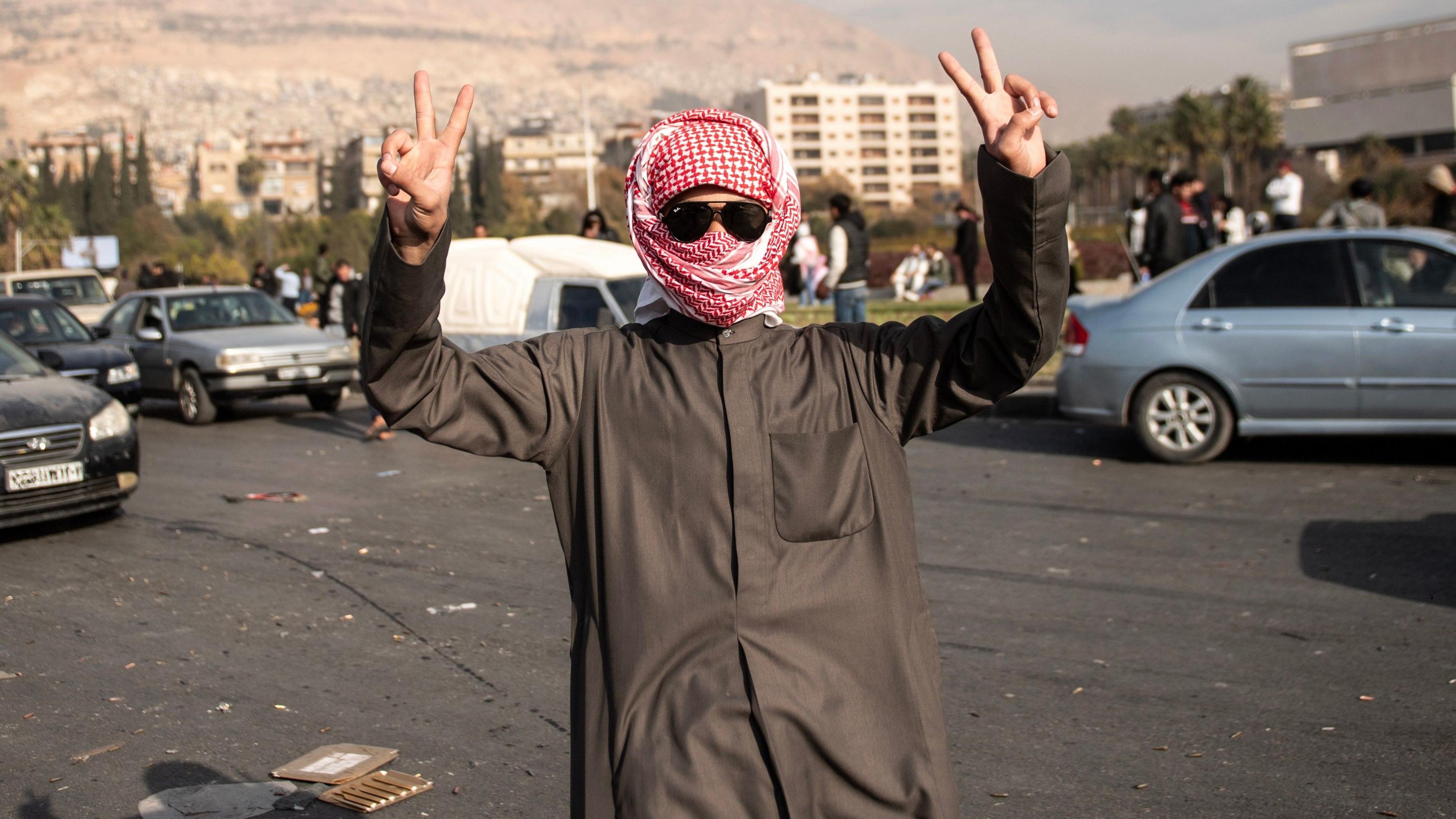 People celebrate in the street after Syrian rebels captured the city of Damascus