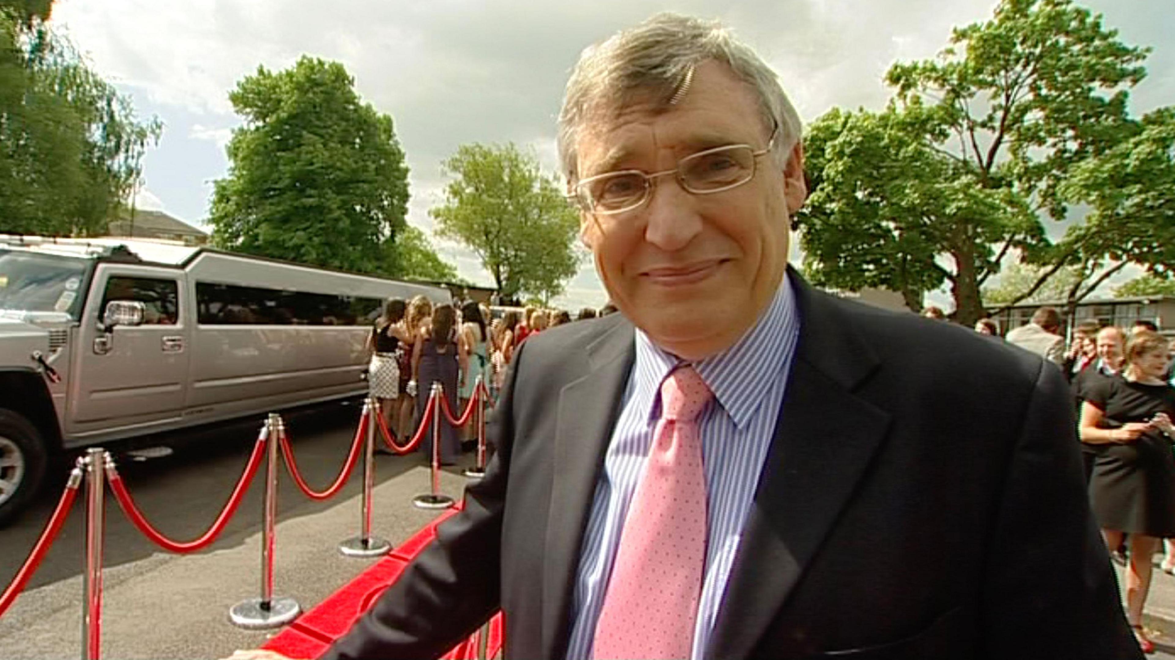 James Roberson in a suit and pink tie in front of a red carpet