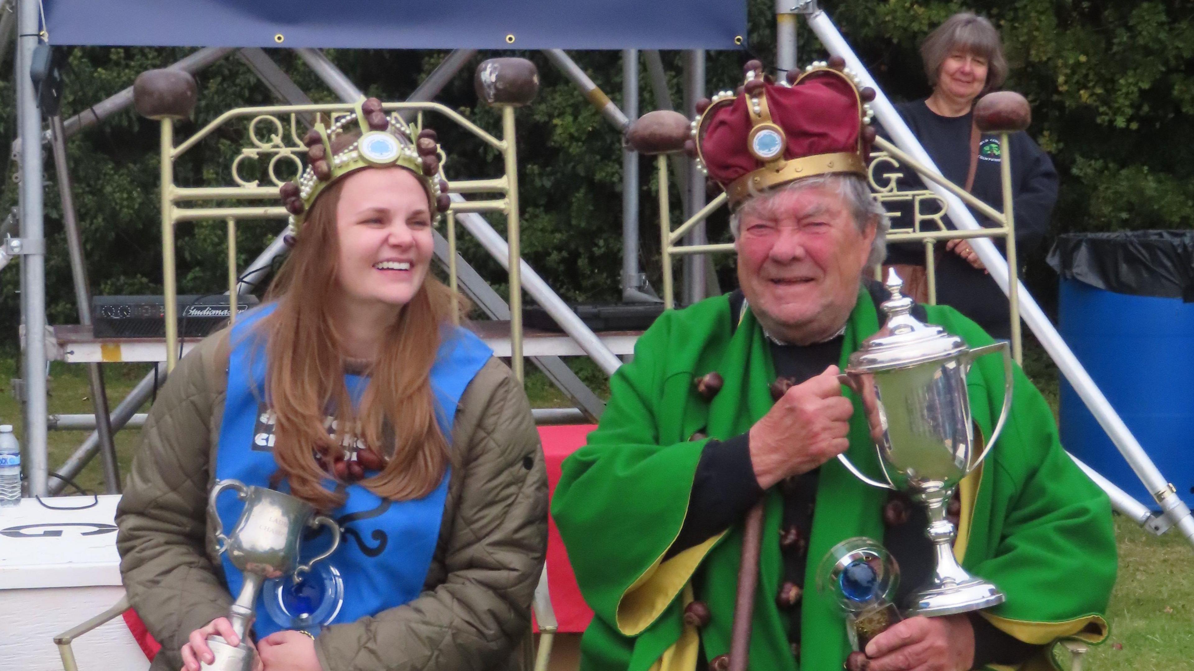 David Jakins and Kelci Banschbach sitting in thrones, decorated with conkers and holding trophies