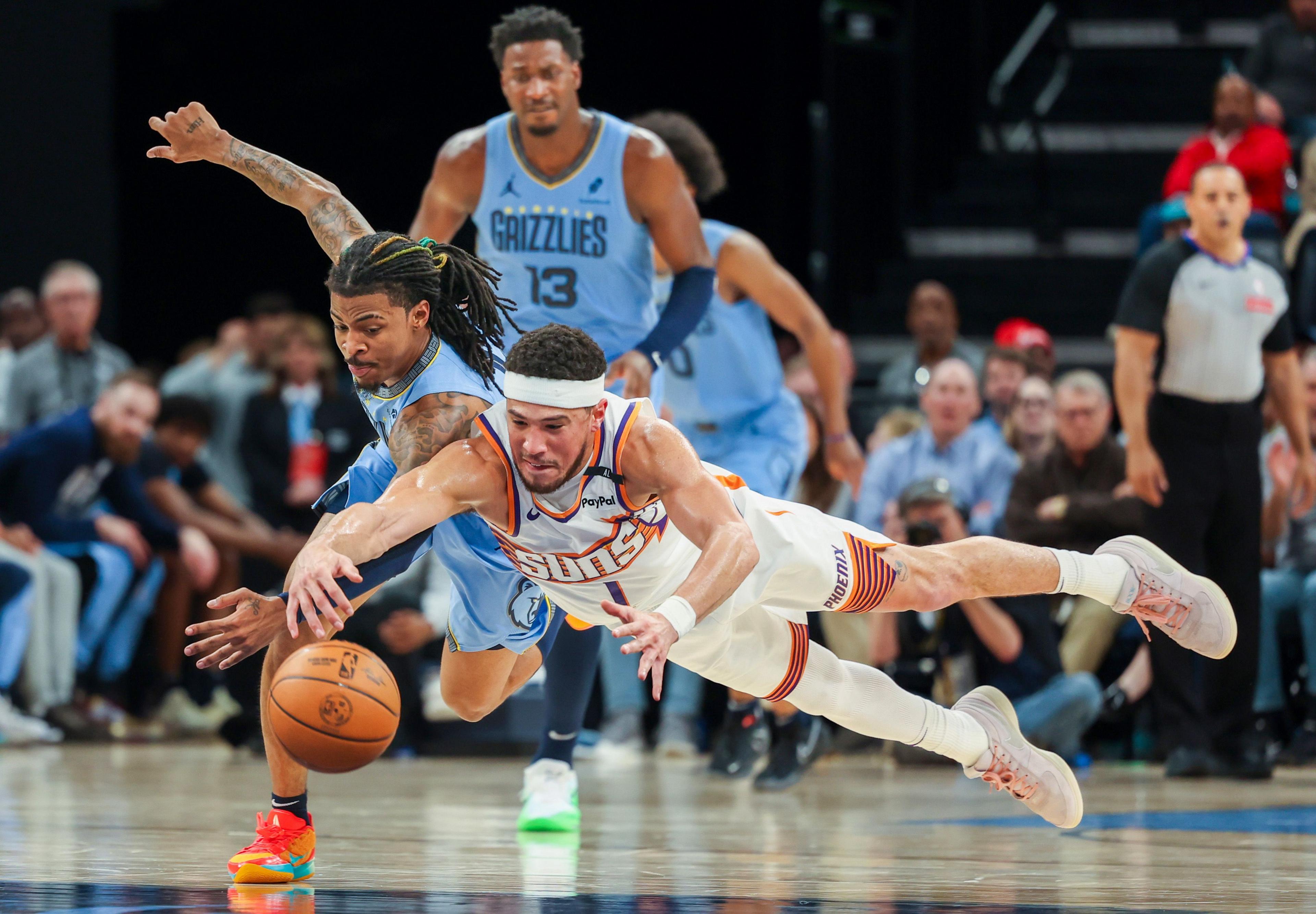 Phoenix Suns Devin Booker and Memphis Grizzlies Ja Morant dive for the ball during the first half of their NBA match in Memphis