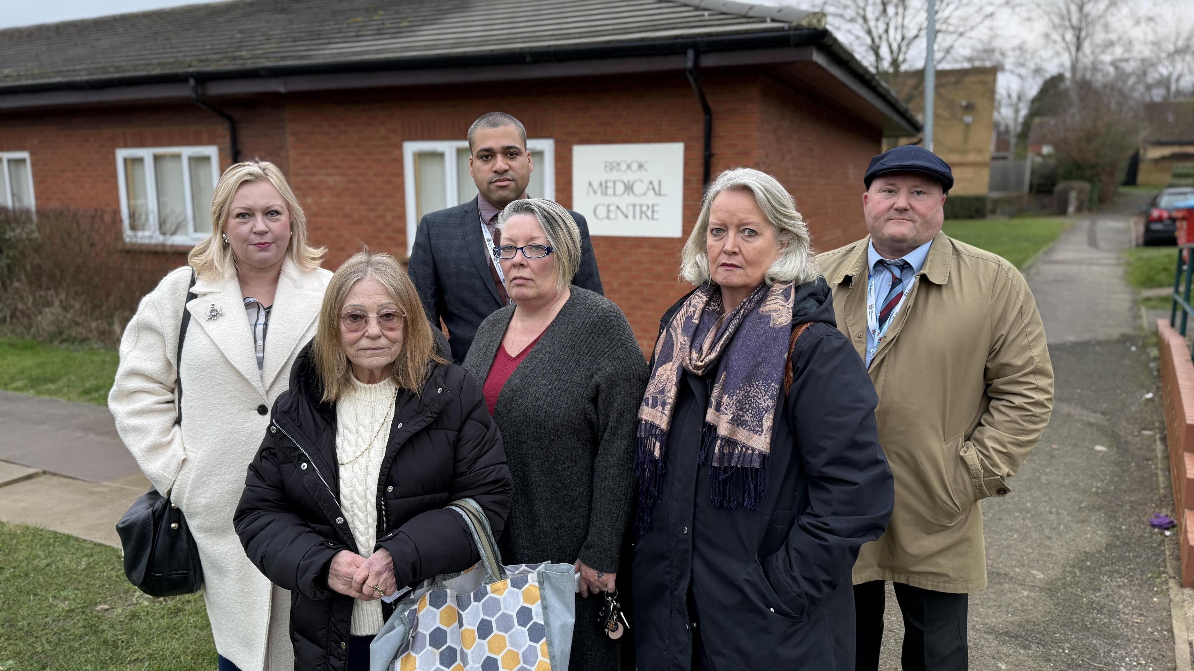 Four middle-aged women patients stood in front of councillors James Hill and Paul Clarke outside Brook Medical Centre 