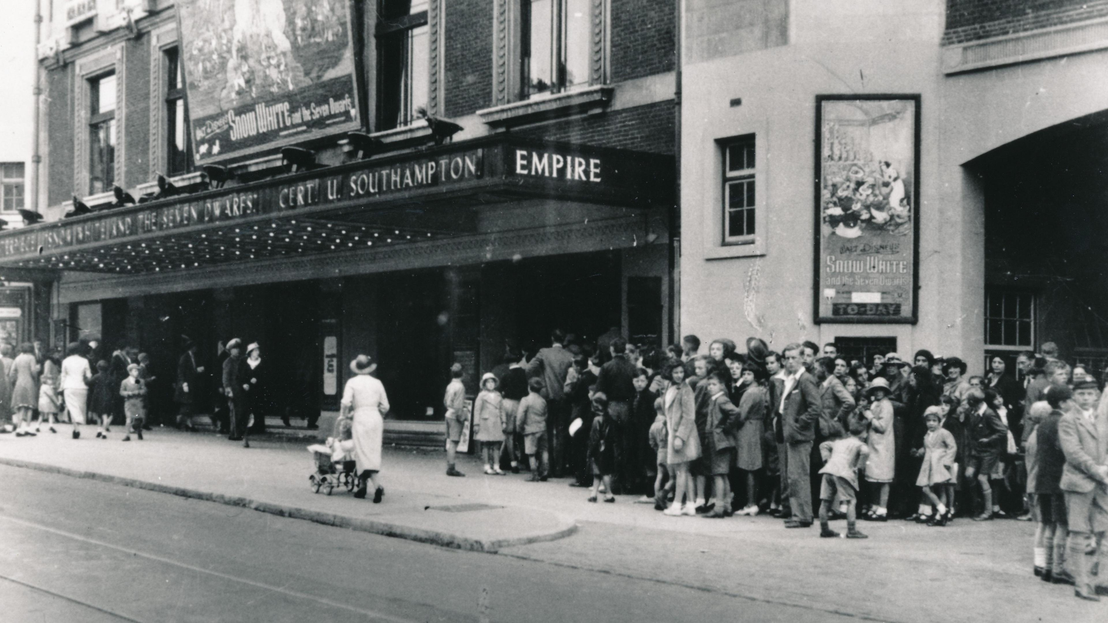 An archive black and white picture of the Empire Theatre dating from the 1930s with crowds outside queuing for a production of Snow White, advertised above the front entrance.