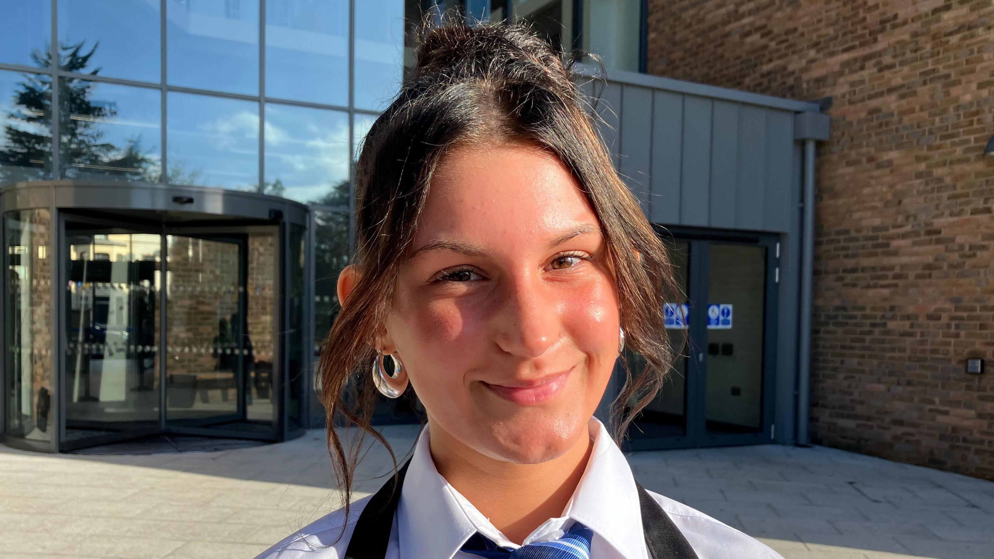  Zuzanna Gestwicka is wearing a striped tie, white shirt and apron. She has large earrings and her hair tied up in a bun.