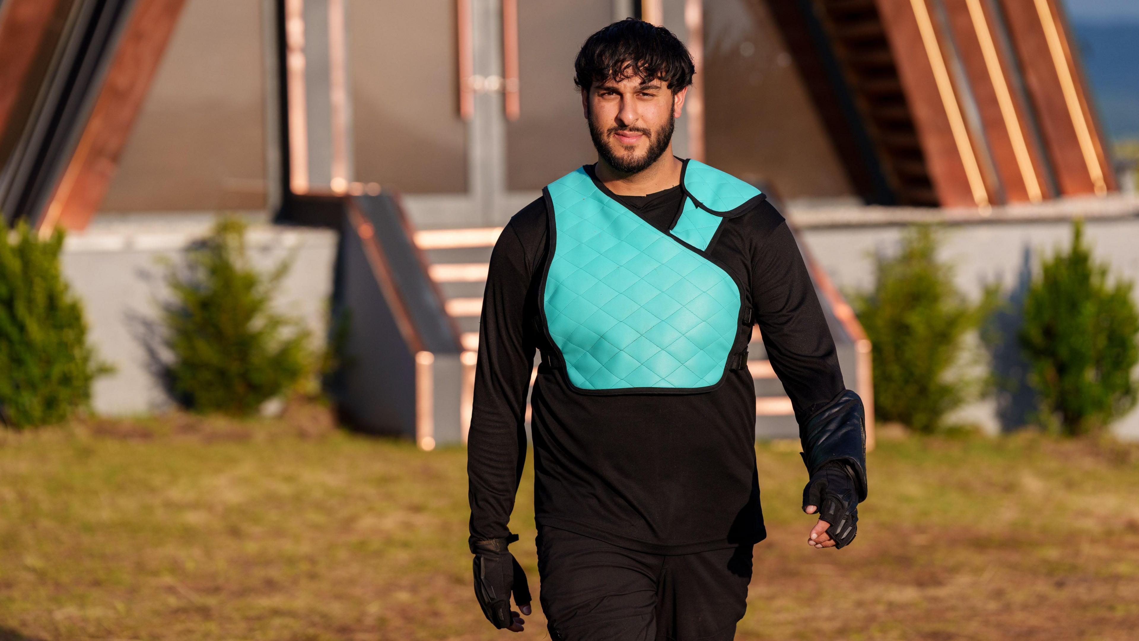 Ameer, fel 'Prey', yn ei fest wyrddlas