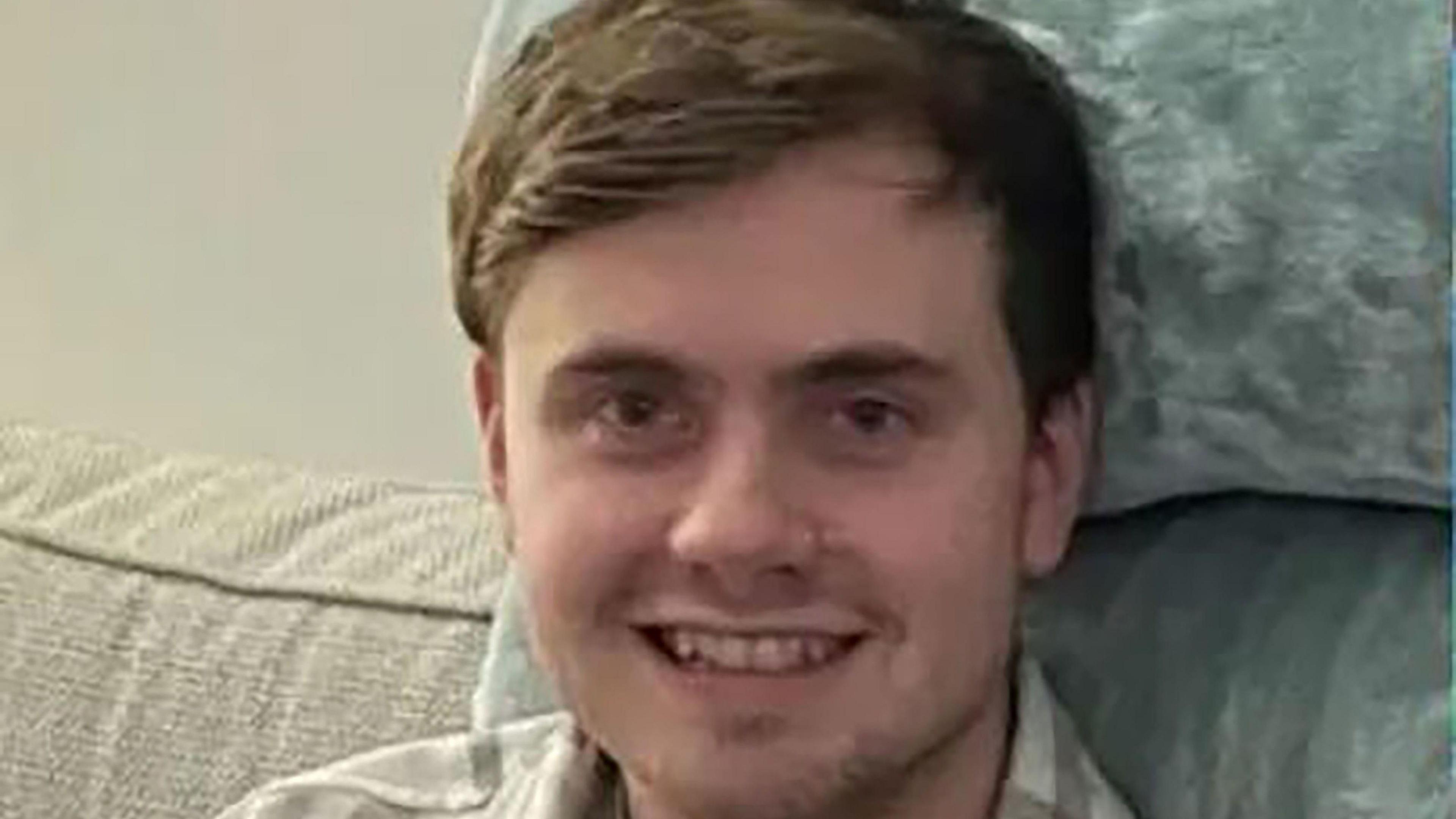 A family picture of missing Bristol student Jack O'Sullivan who is sat on a sofa smiling at the camera.