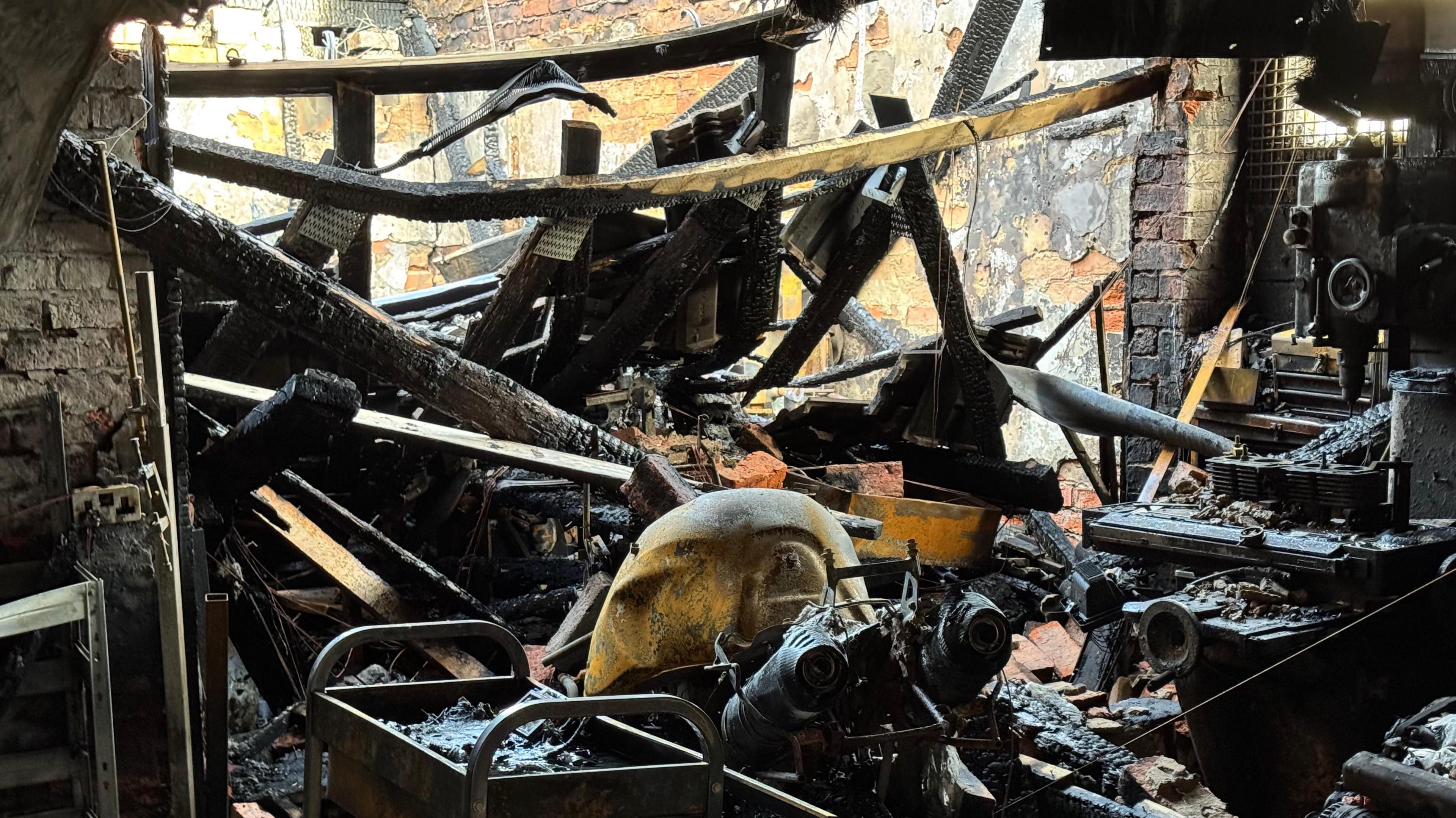 The inside of the shop has charred items inside and a collapsed wall. 