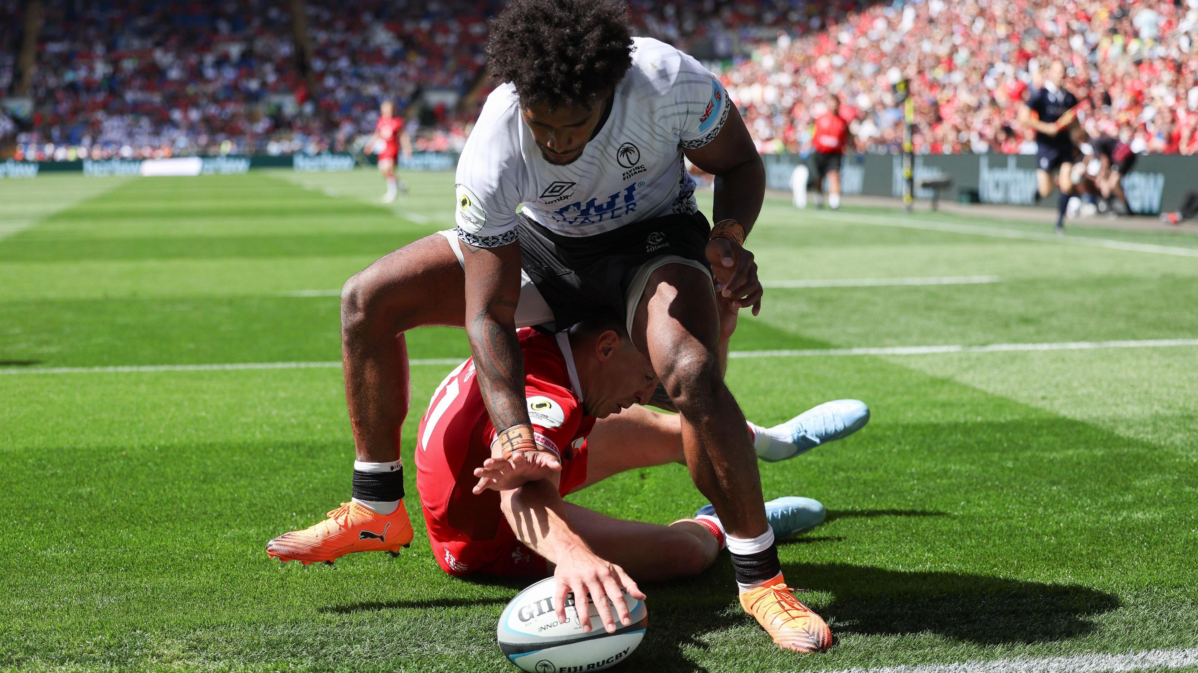 Josh Adams grounds the ball after diving through Selestino Ravutaumada's legs