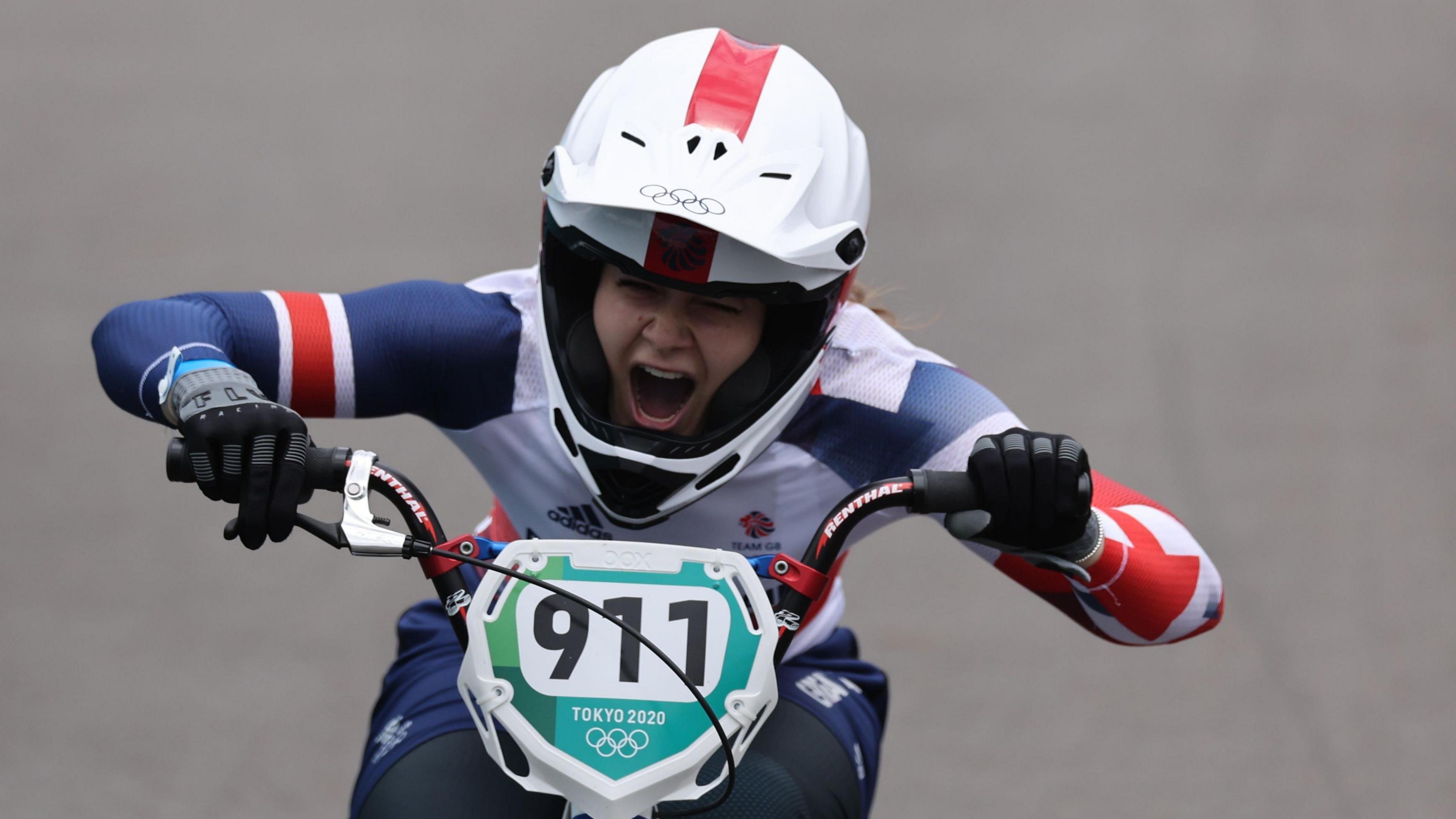 A woman riding a quad bike. She is wearing a helmet with her mouth open 